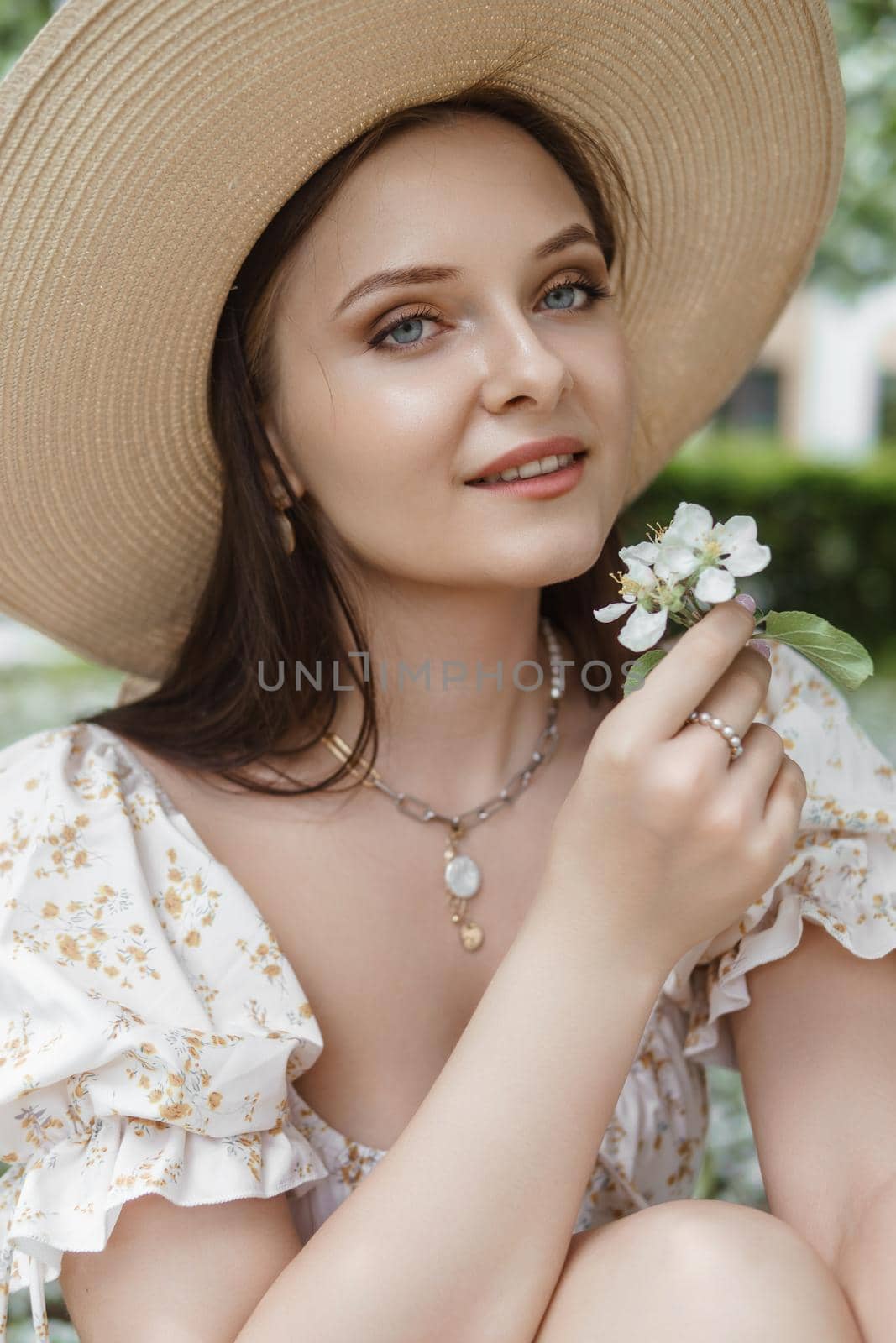 An attractive long-haired woman walks in the spring in the park of blooming apple trees. Spring portrait of a woman