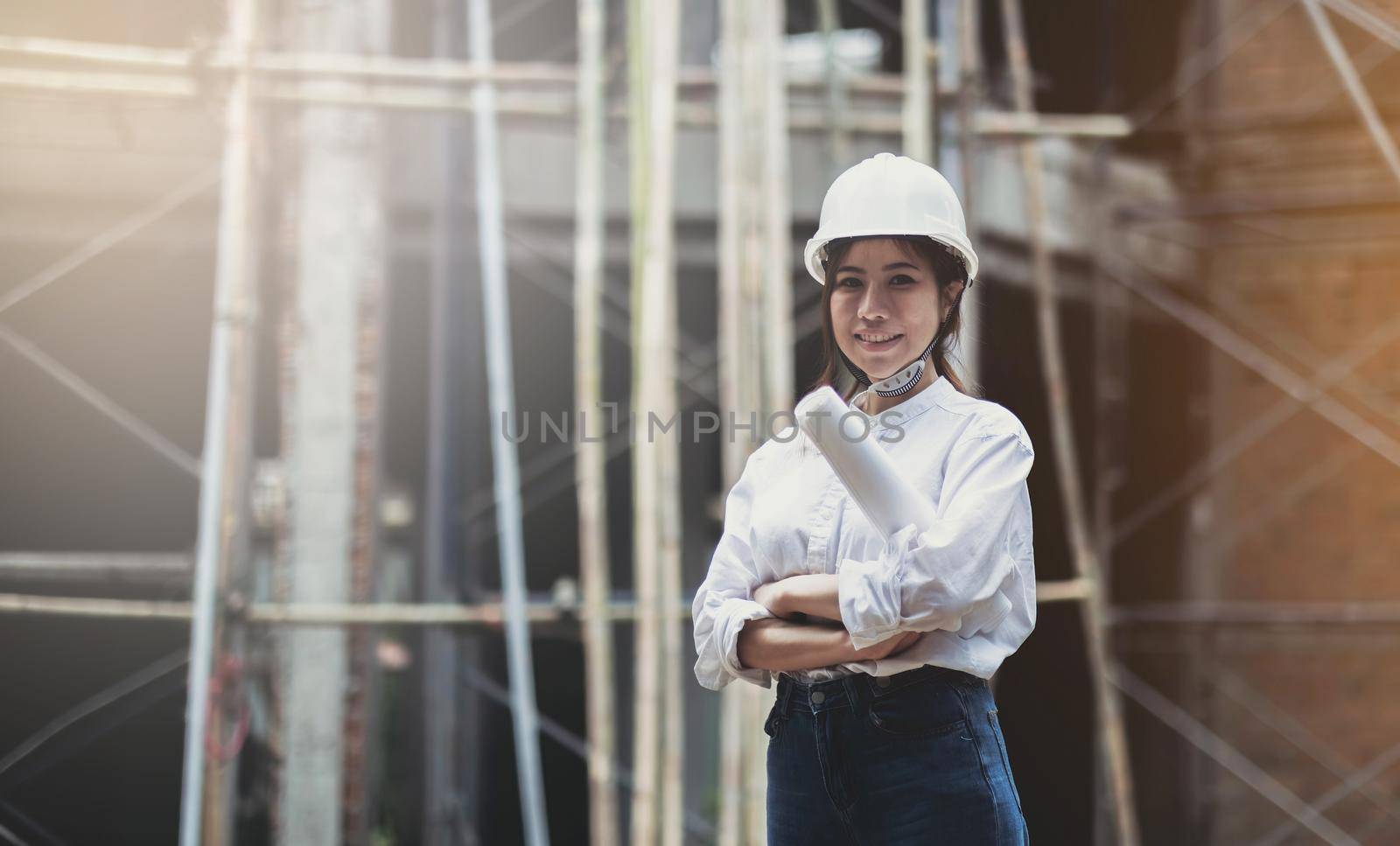 Female construction engineer. Portrait of a young woman working at a construction site. by wichayada