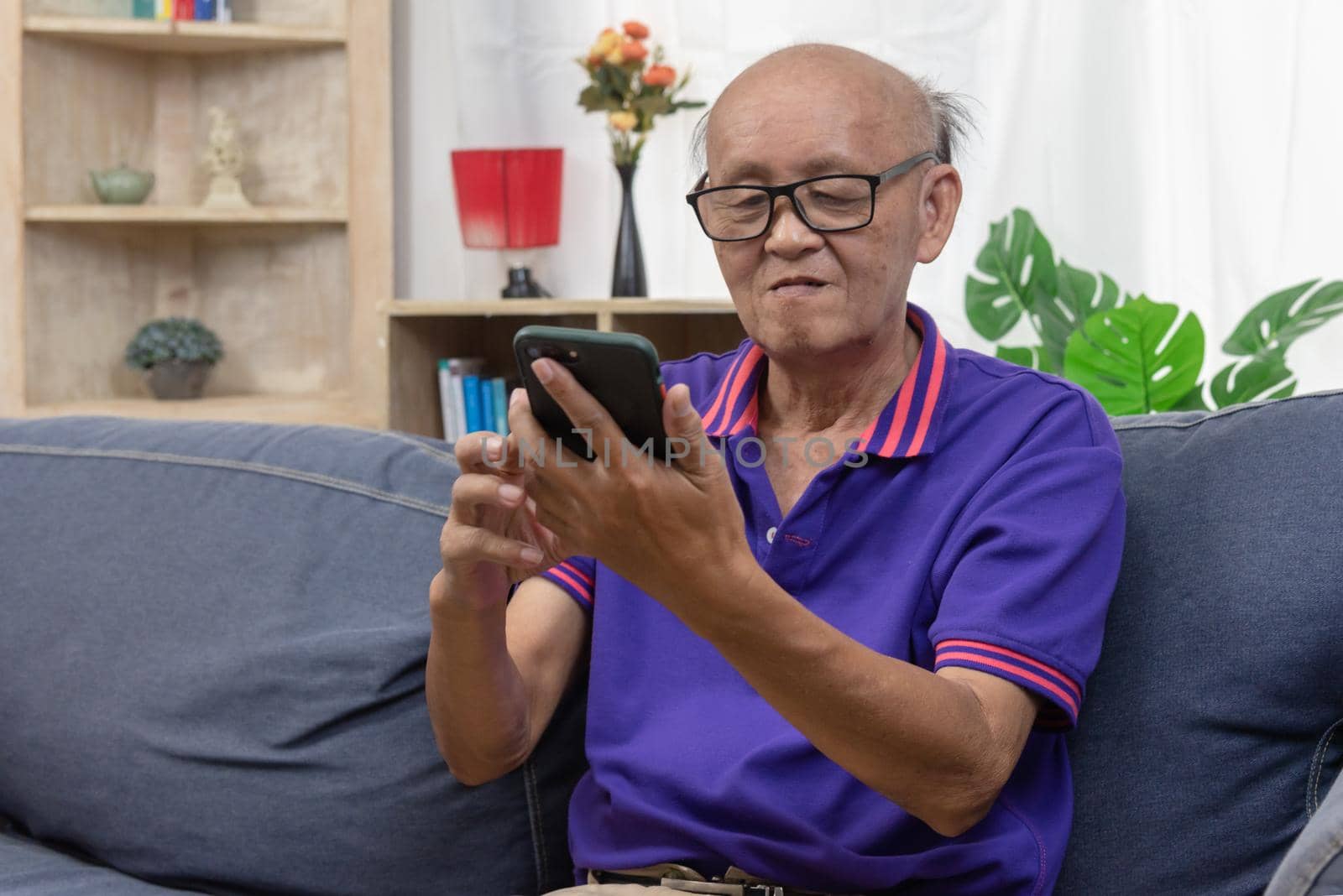 Asian elderly man using mobile phone connection online internet communication technology at home. by aoo3771