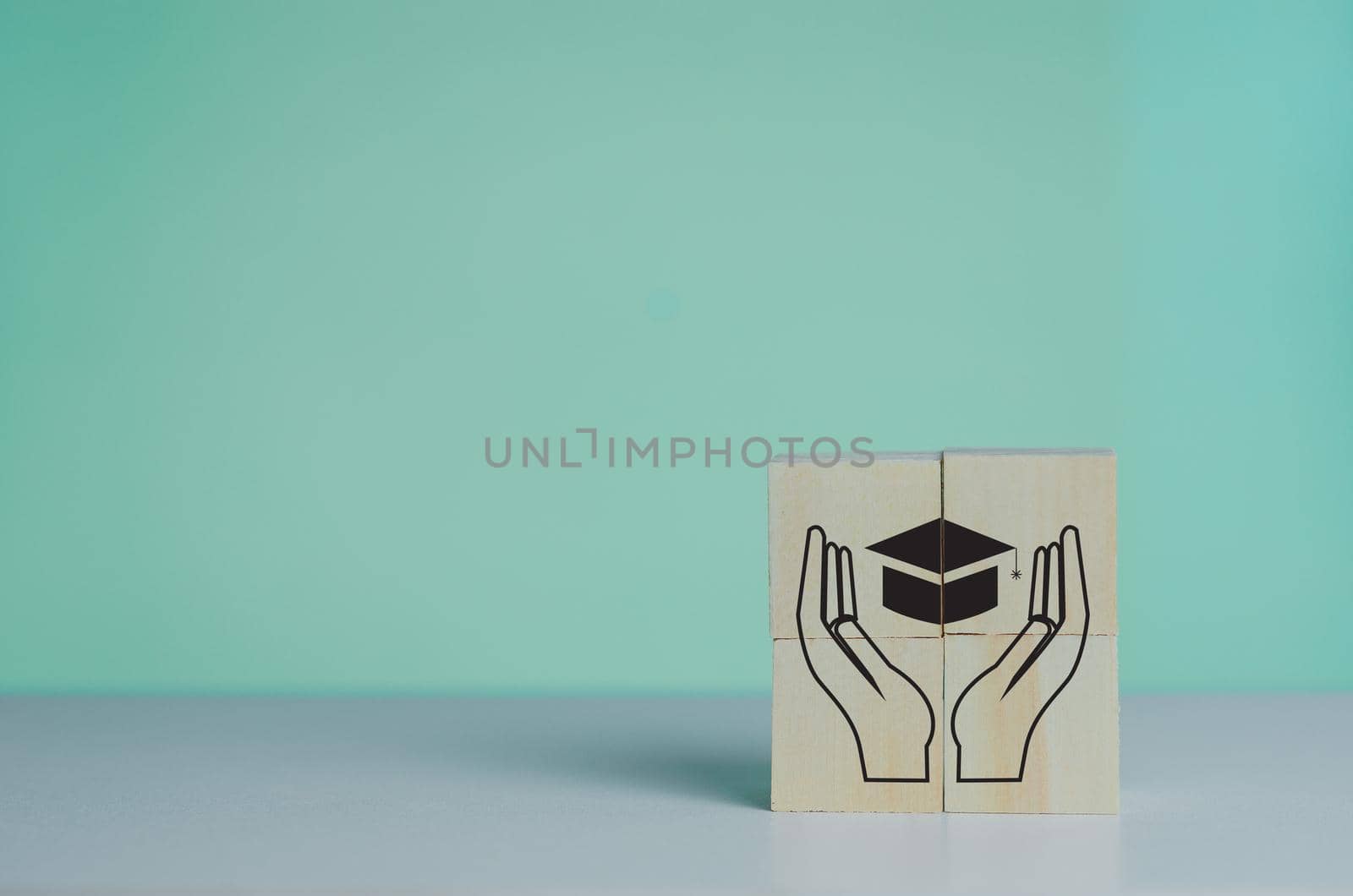 Wooden cube with graduation cap icon.Education concept. Graduation day success on background copy space. by aoo3771