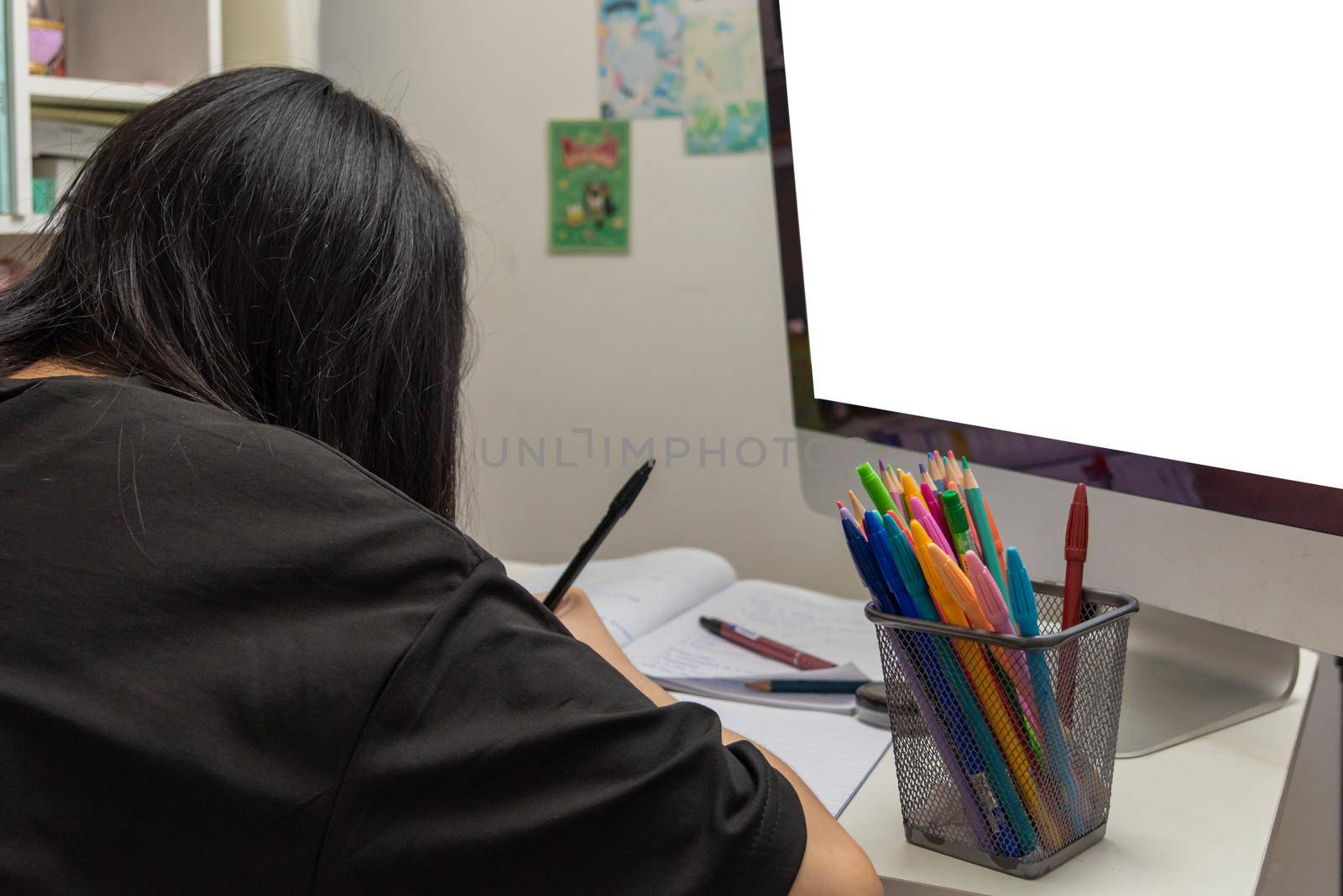 Asian student girl is writing homework and reading book at desk by aoo3771