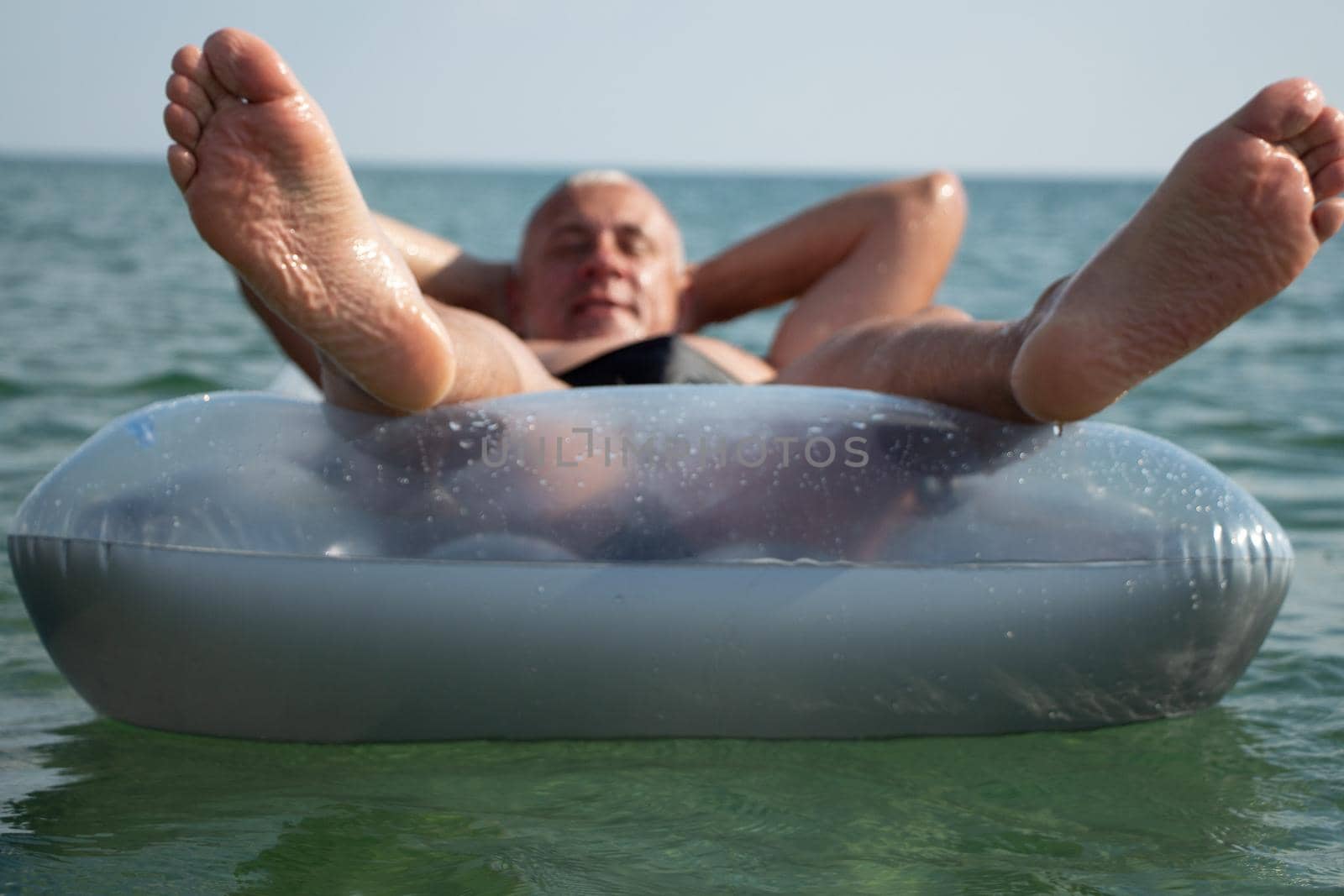 A man at sea with an air mattress. Beach vacation.