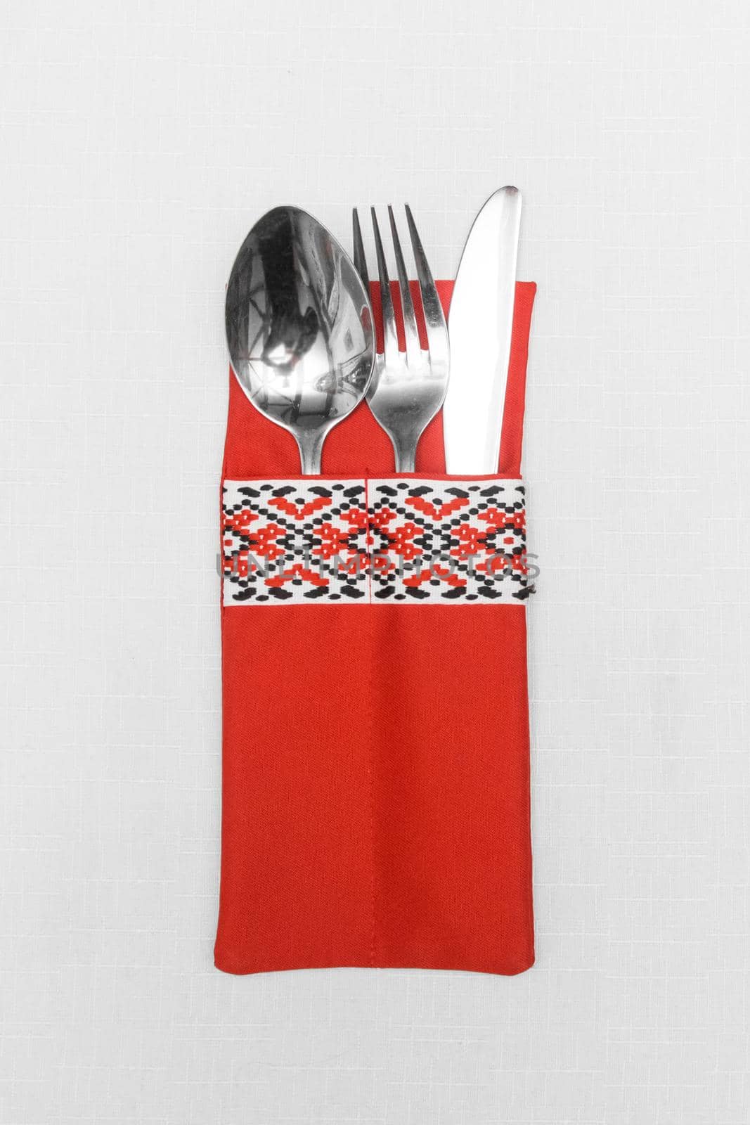 Spoon fork and knife cutlery utensil silverware in traditional ornament style on white tablecloth background.