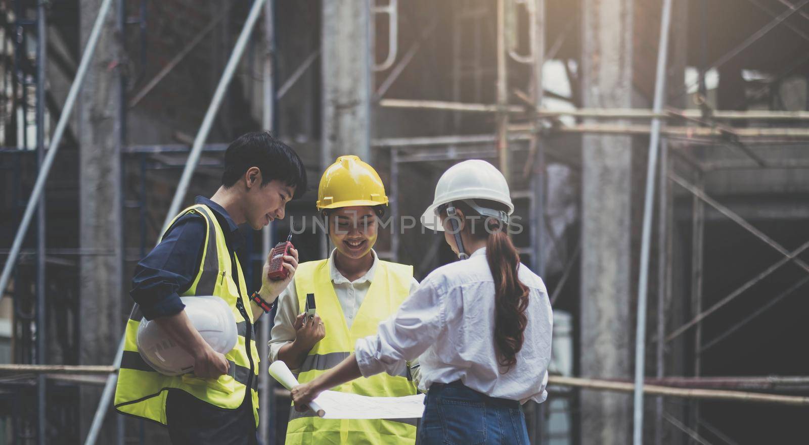 A diverse team of experts are planning on the construction site. Real estate project with civil engineers, architects, business investors and the general staff are discussing the details of the plans..