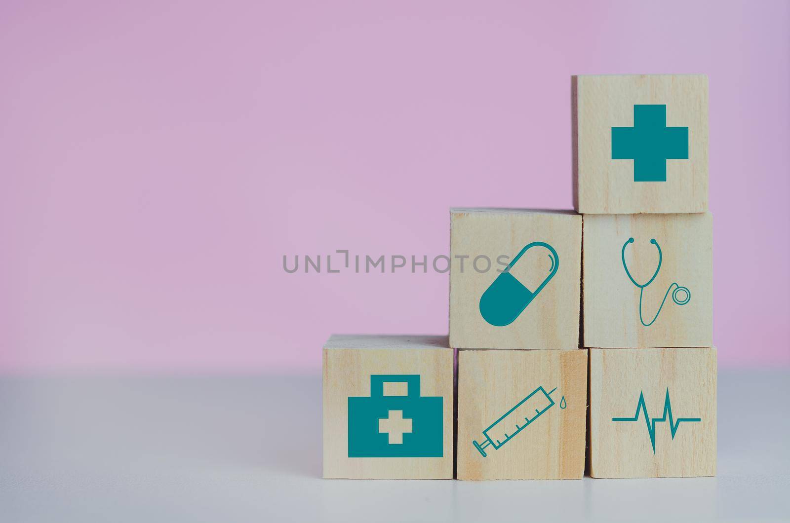 Wooden cubes block with insurance health car medical symbol on the pink background and copy space.