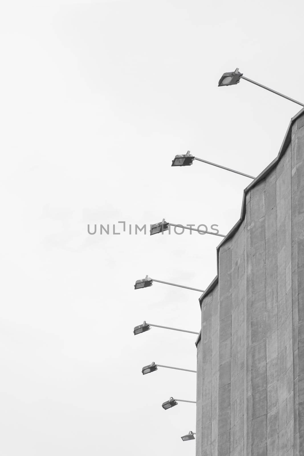 Concrete old building architecture structure cement facade apartment stone with elements of illumination bulbs on the roof against a background of gray sky.