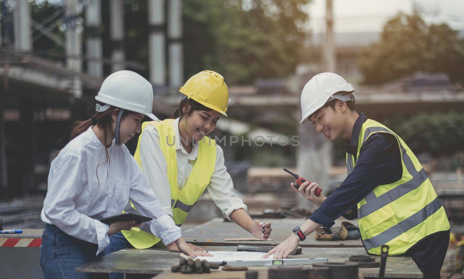 Asian woman civil engineer paper plan building architect wearing white safety helmet look at contruction site.Female foreman in a construction helmet, facemask, by wichayada