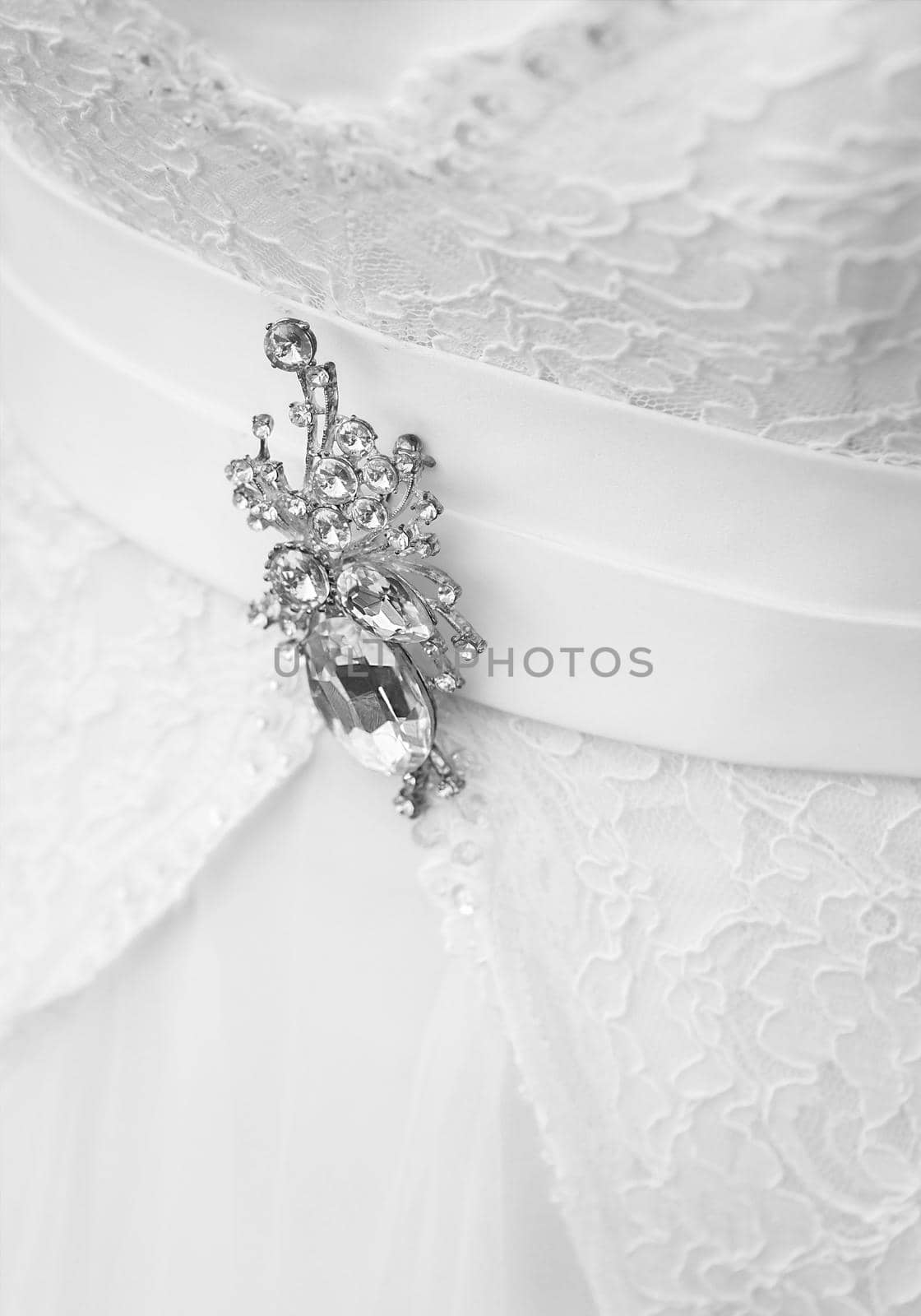 Decoration brooch with diamonds on the wedding white dress of the bride, close-up.