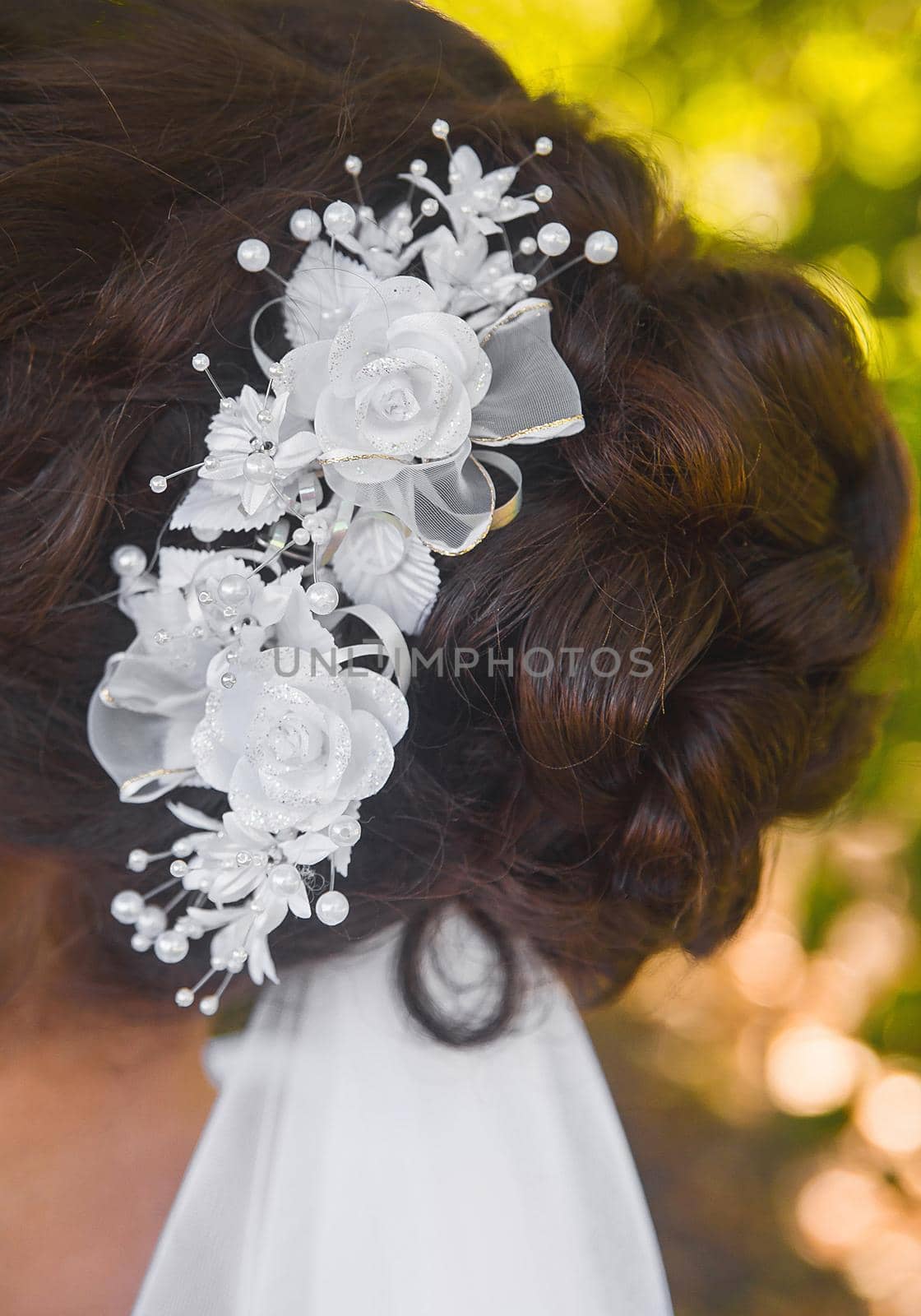 Wedding hairstyle bride brunette with white roses decoration, close-up.