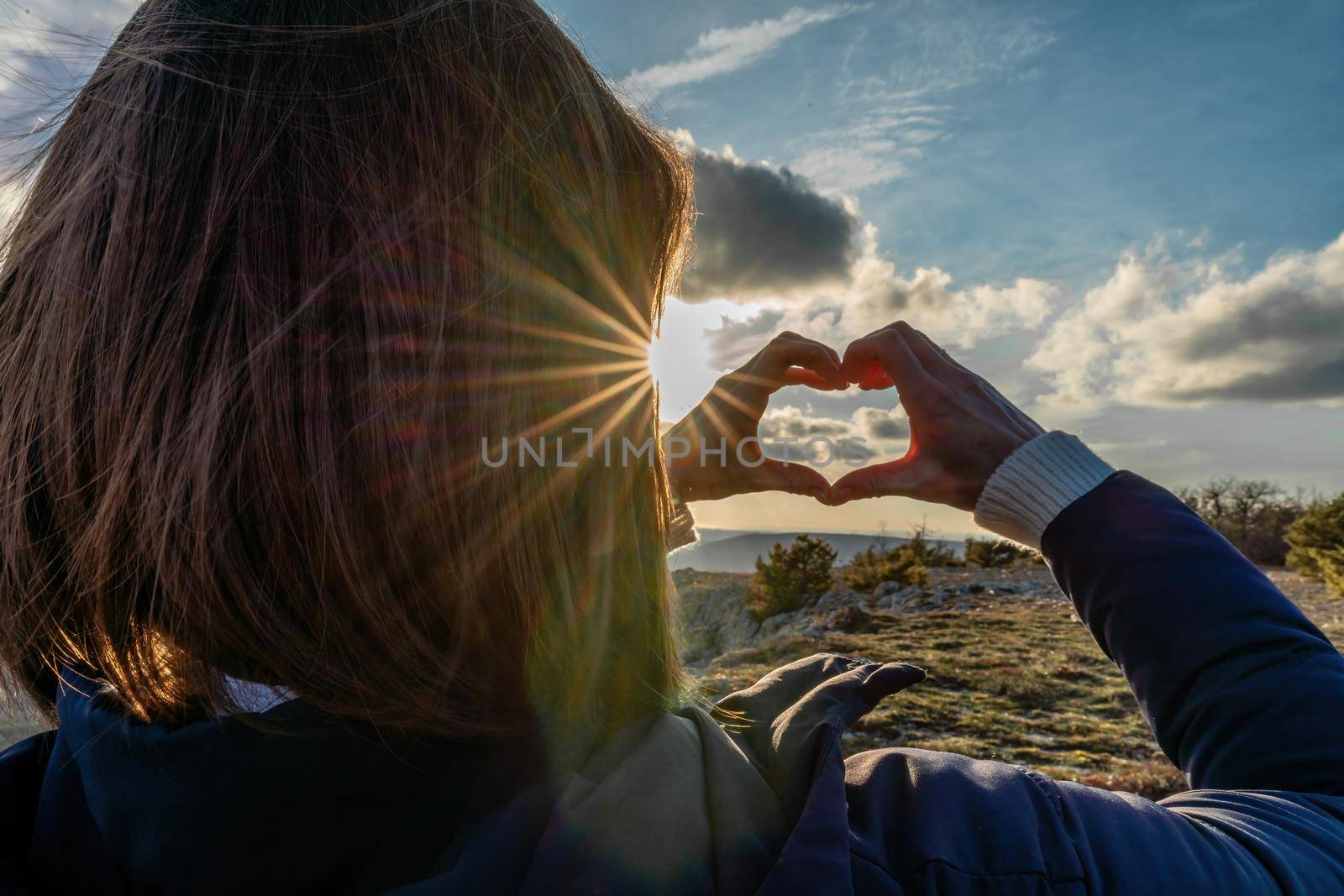 The girl made a beautiful heart from her finger in the rays of the sun. healthy woman making heart shape with hands at sunset. Shining summer sun on your hands. healthy heart concept