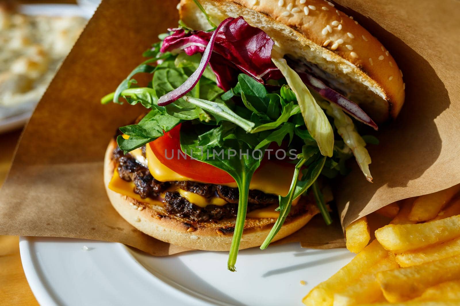Big burger with beef cutlet and salad in a paper envelope