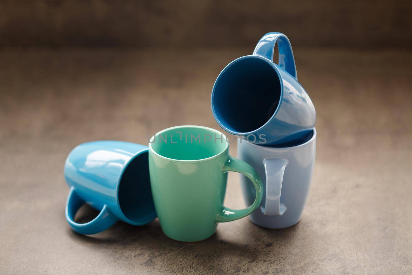 four tea mugs of different colors on a gray background