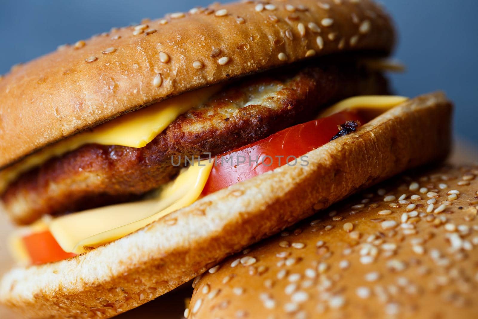 Large juicy burger with cutlet cheese and tomatoes. Fast food