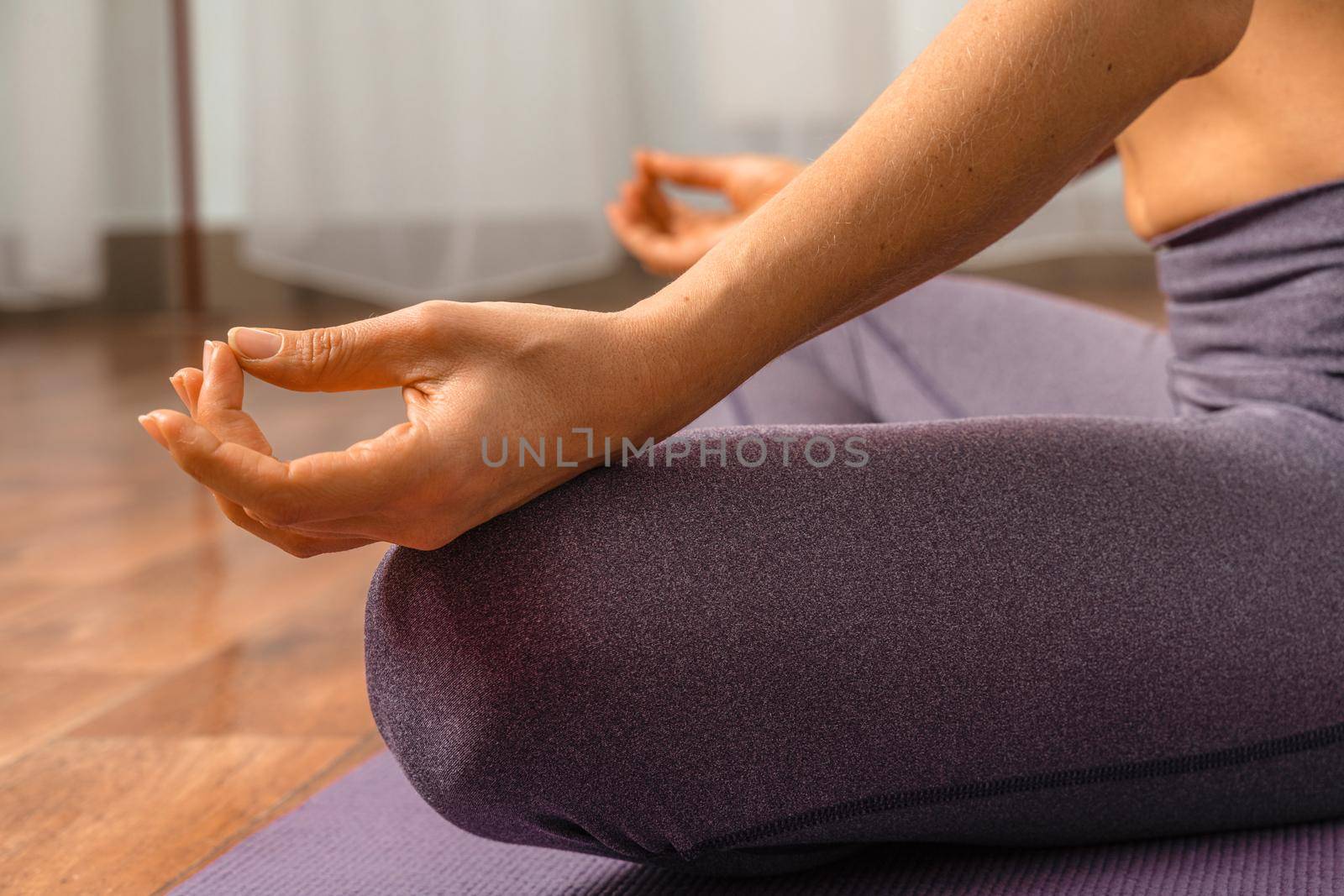 Young woman meditating in the lotus pose at home. Practicing yoga indoors. Harmony, yoga practice, balance, meditation, relaxation at home, healthy lifestyle concept. by Matiunina