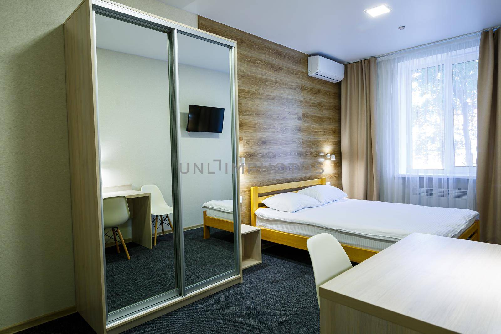 Large bright room in the hotel with a bed, TV, wardrobe. White bedding. Hotel room