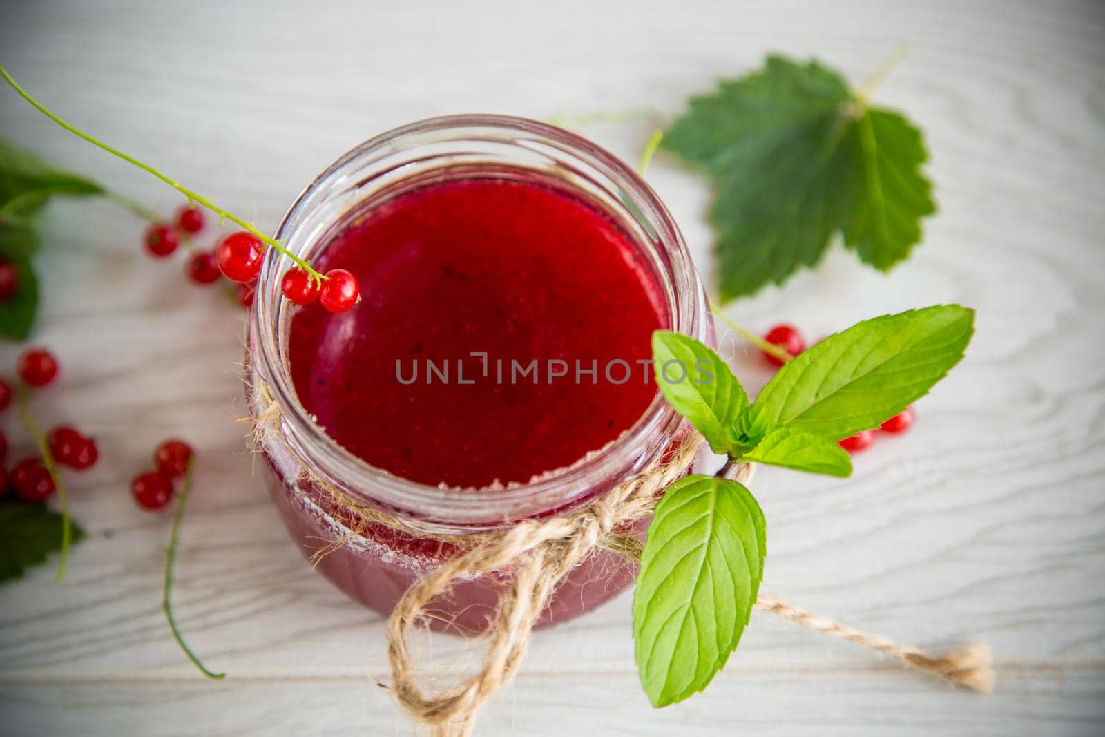 sweet summer jam from ripe red currants in a jar on a wooden table