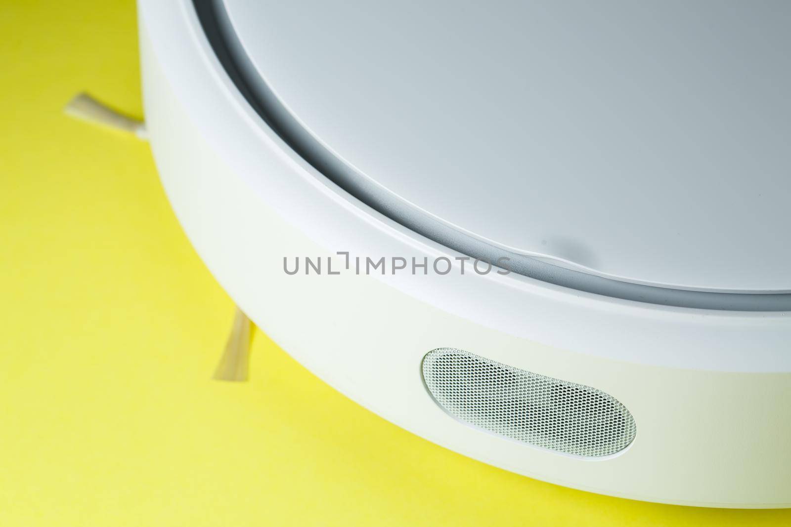 white robot cleaner for cleaning the house on a yellow background