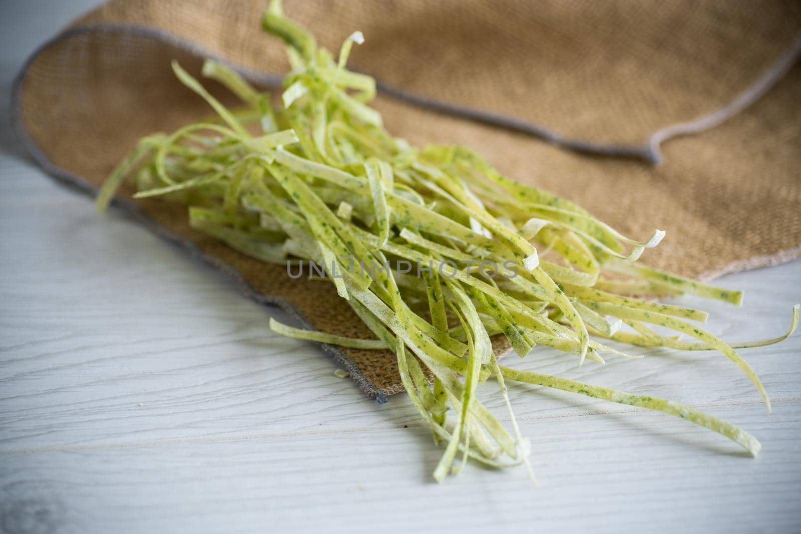 dried homemade green raw noodles with herbs on a wooden table