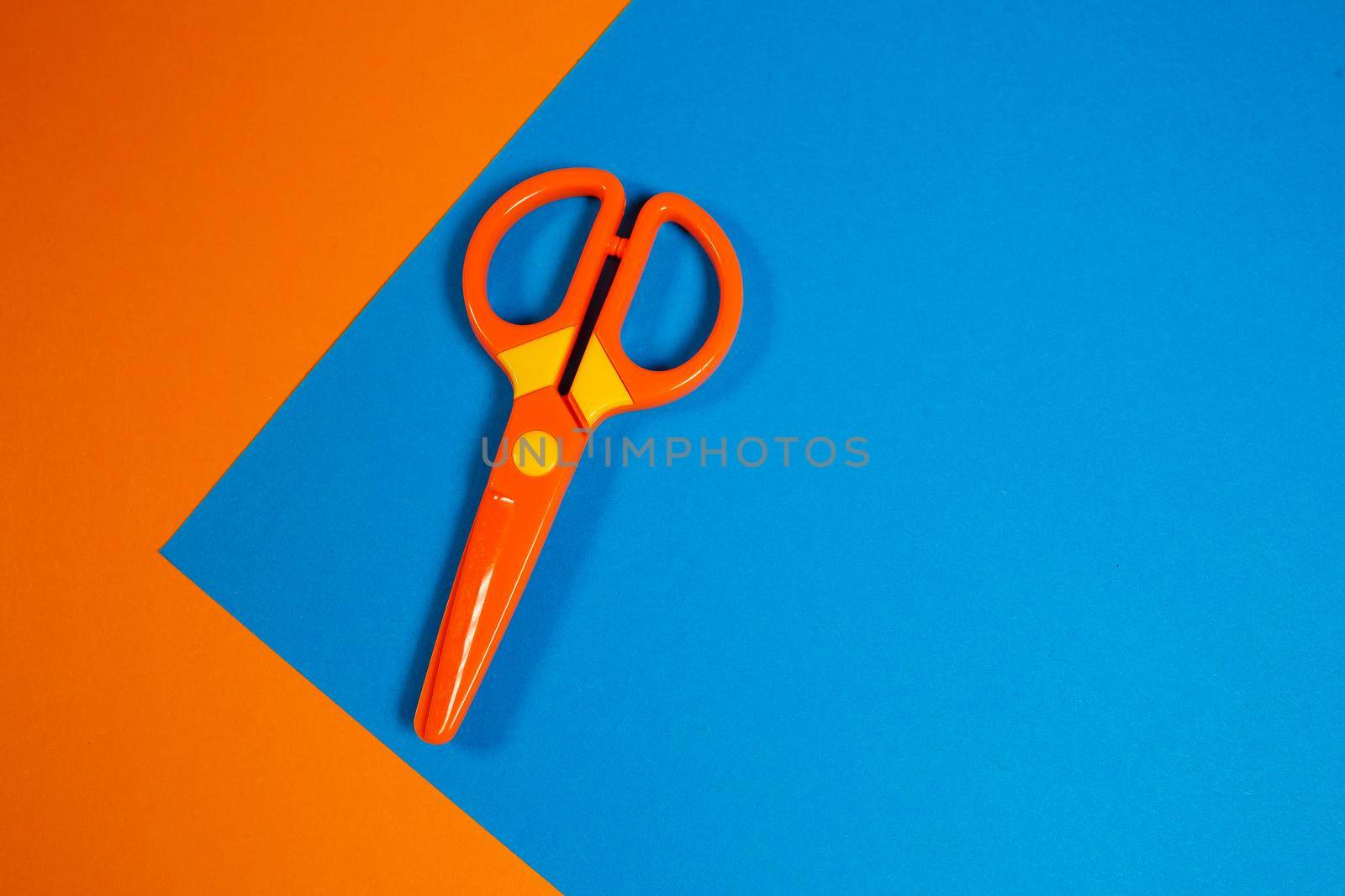 Children's plastic scissors for cutting paper figures on a colored background