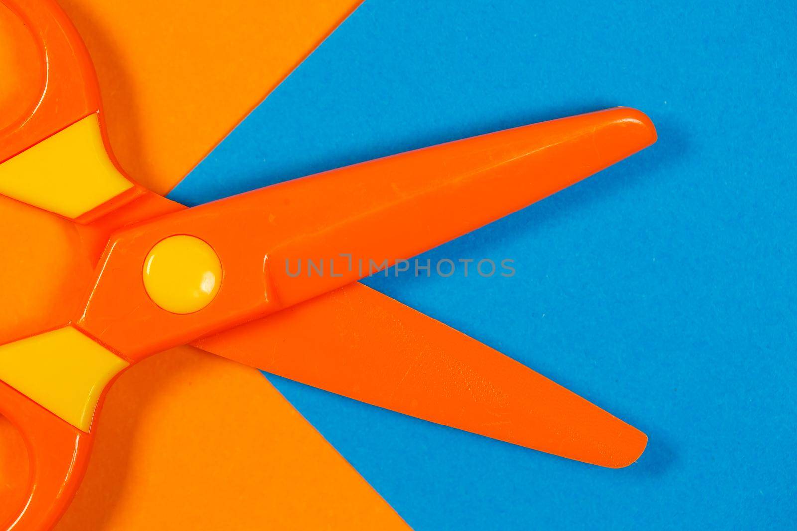Children's plastic scissors for cutting paper figures on a colored background