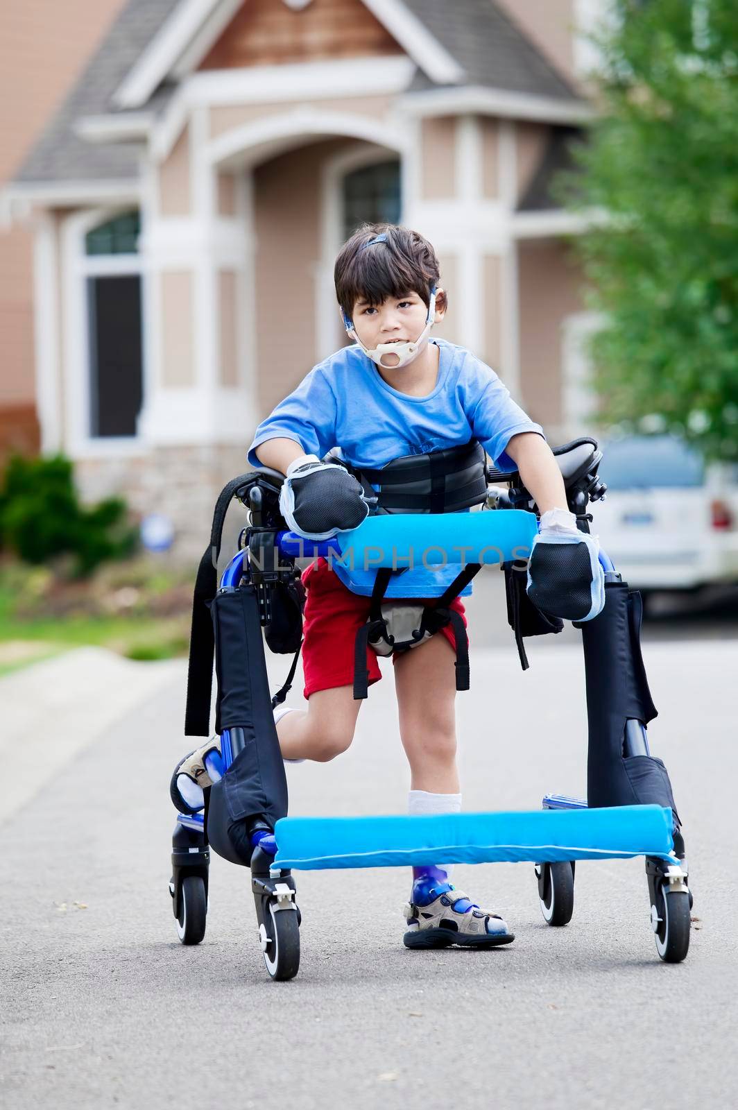 Six year old disabled boy walking in walker down the street by jarenwicklund