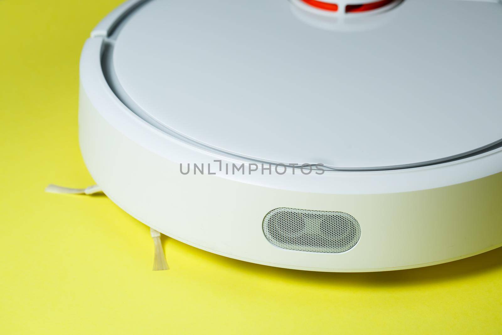 white robot cleaner for cleaning the house on a yellow background