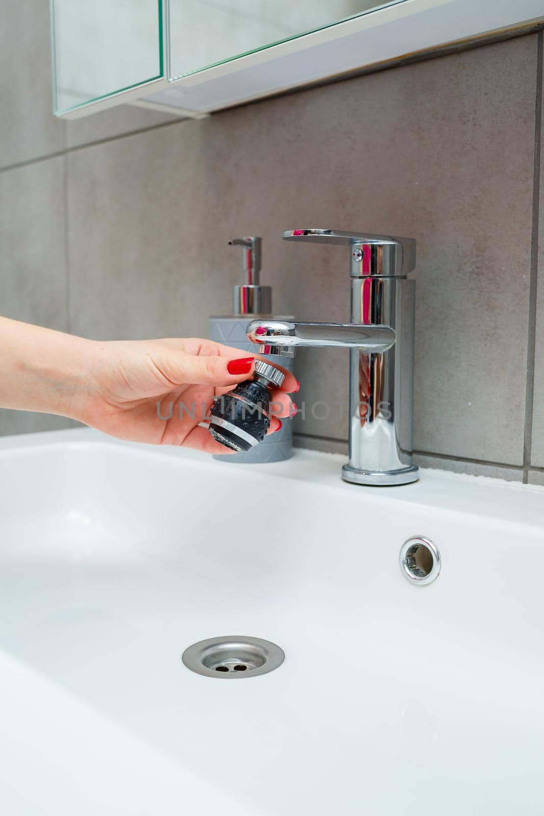 Rotary nozzle on the mixer to adjust the flow of water. White bathroom sink for washing hands