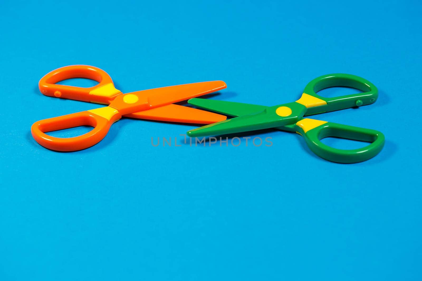 Children's plastic scissors for cutting paper figures on a colored background
