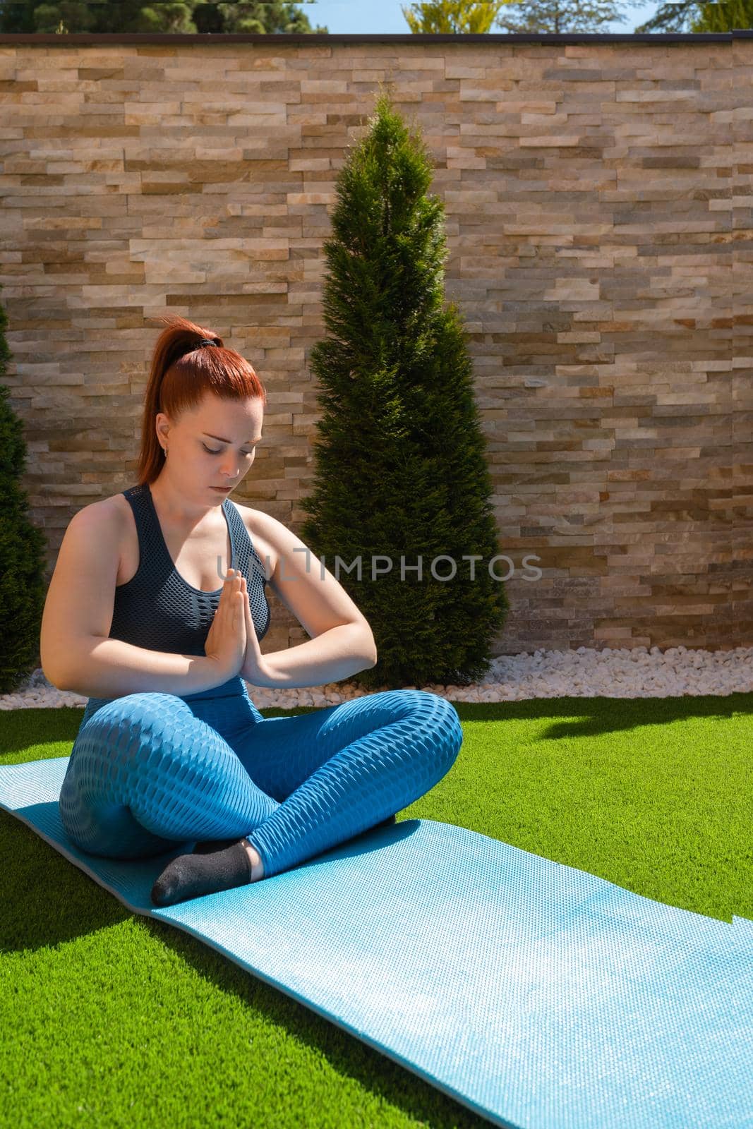 young woman practising meditation in the garden in the open air, relaxation exercises, doing the lotus posture. copy space. concept of health and well-being. natural outdoor light.