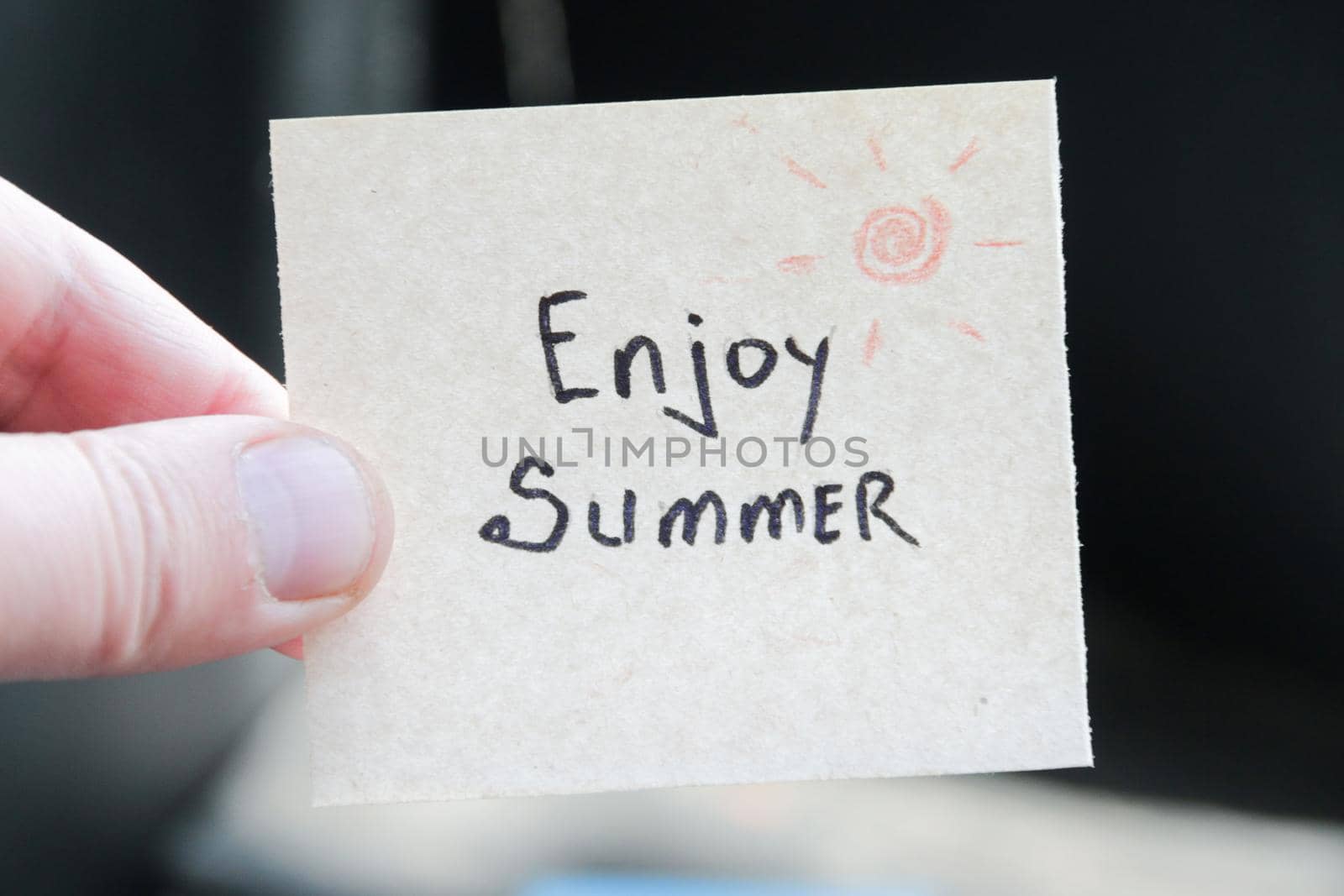 Enjoy summer. Creative concept. Hand holding a tag with the inscription. by Markgraf