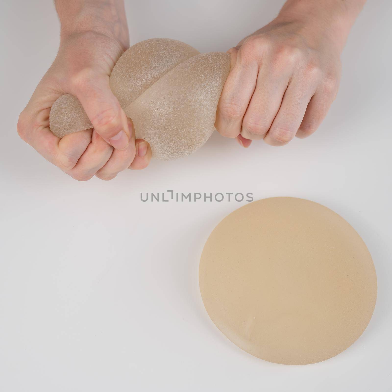 Caucasian woman testing the strength of a breast implant. by mrwed54