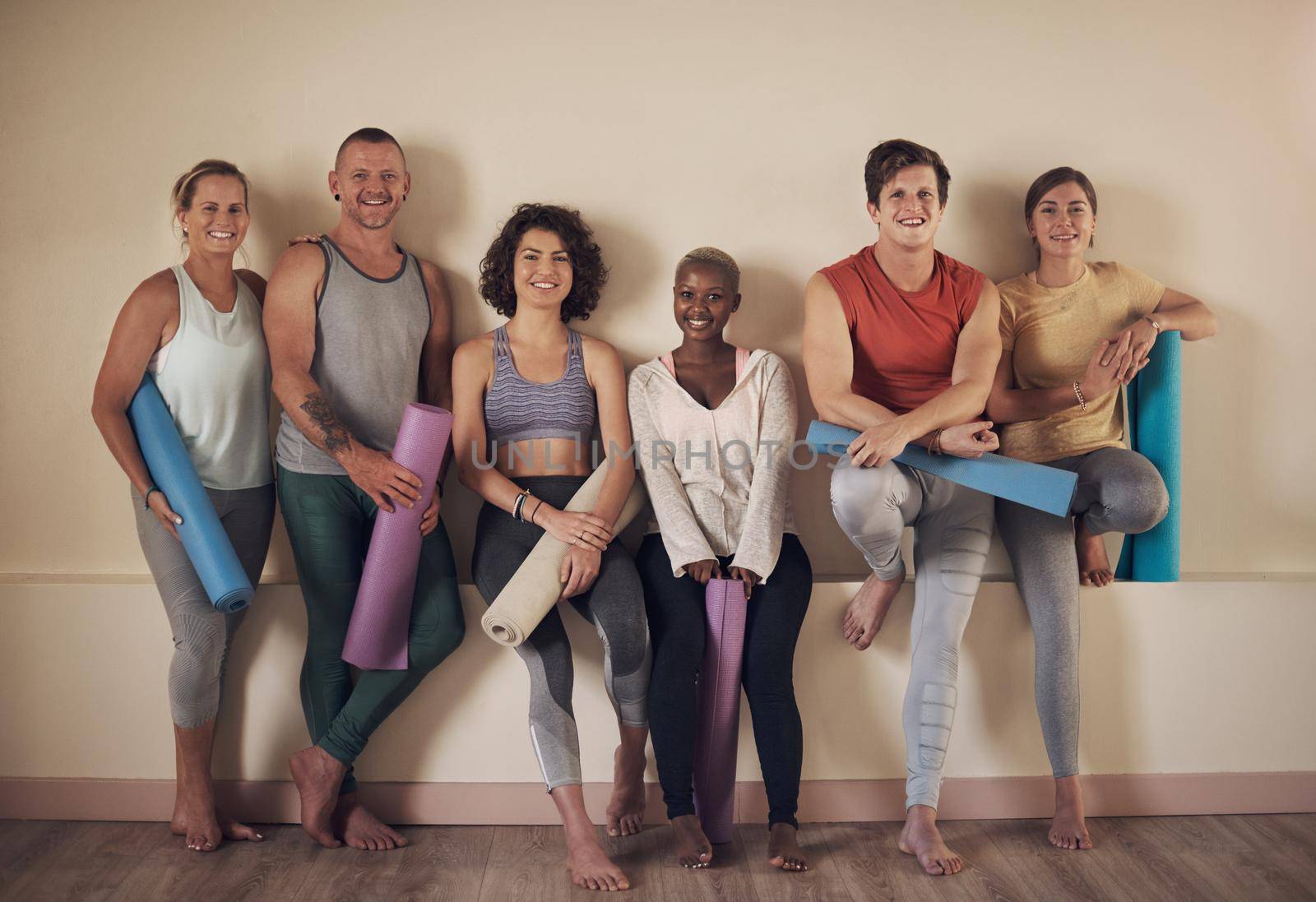 This is the best yoga group. Full length portrait of a diverse group of yogis sitting together and bonding after an indoor yoga session. by YuriArcurs