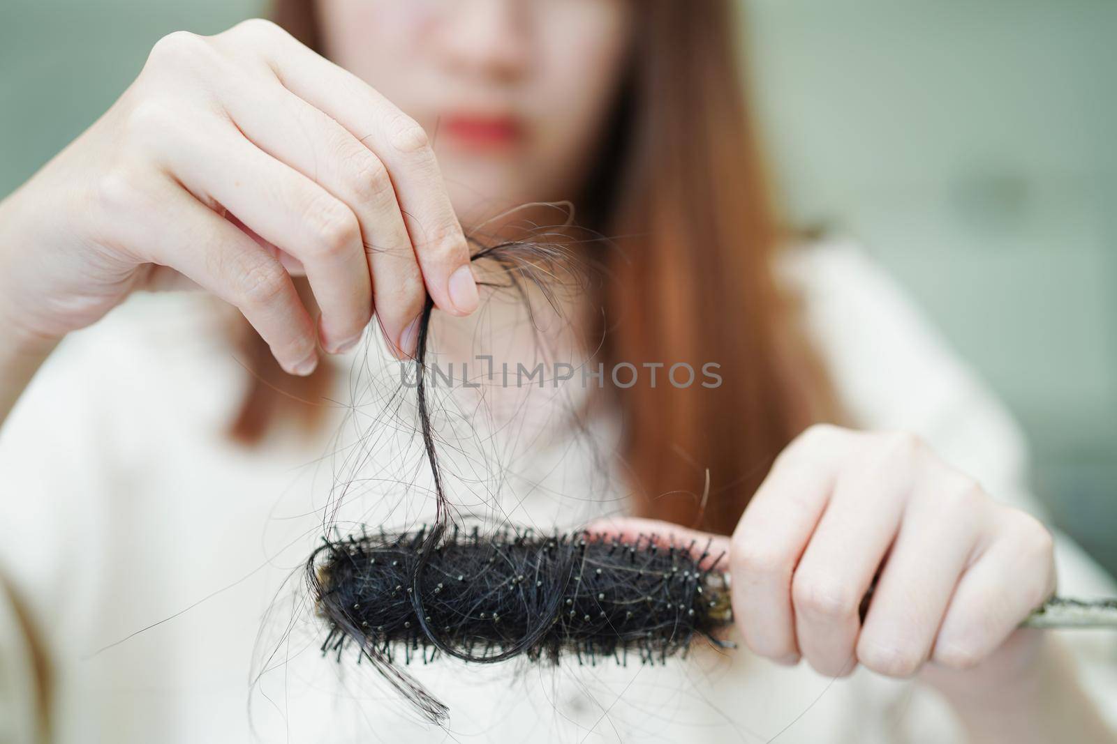 Asian woman have problem with long hair loss attach to comb brush.