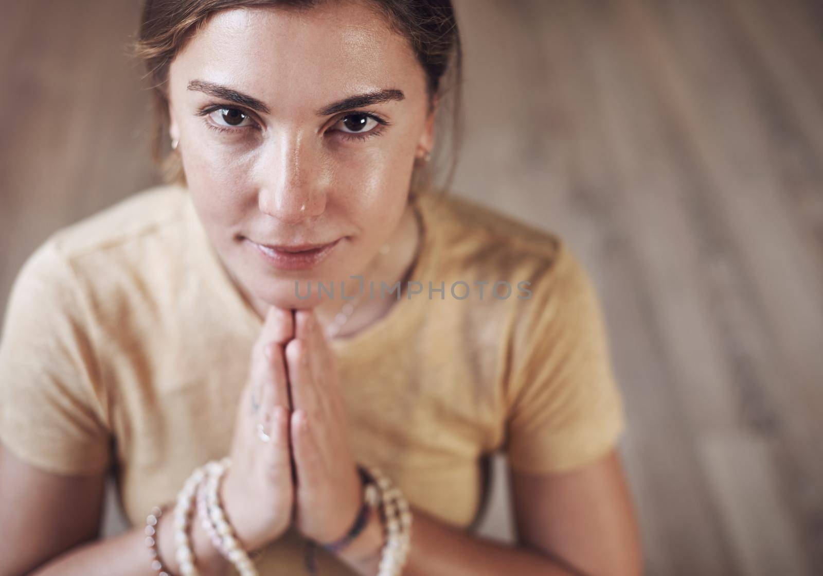 I am at peace with myself. Cropped portrait of an attractive young woman sitting indoors and using mala beads during her meditation routine. by YuriArcurs