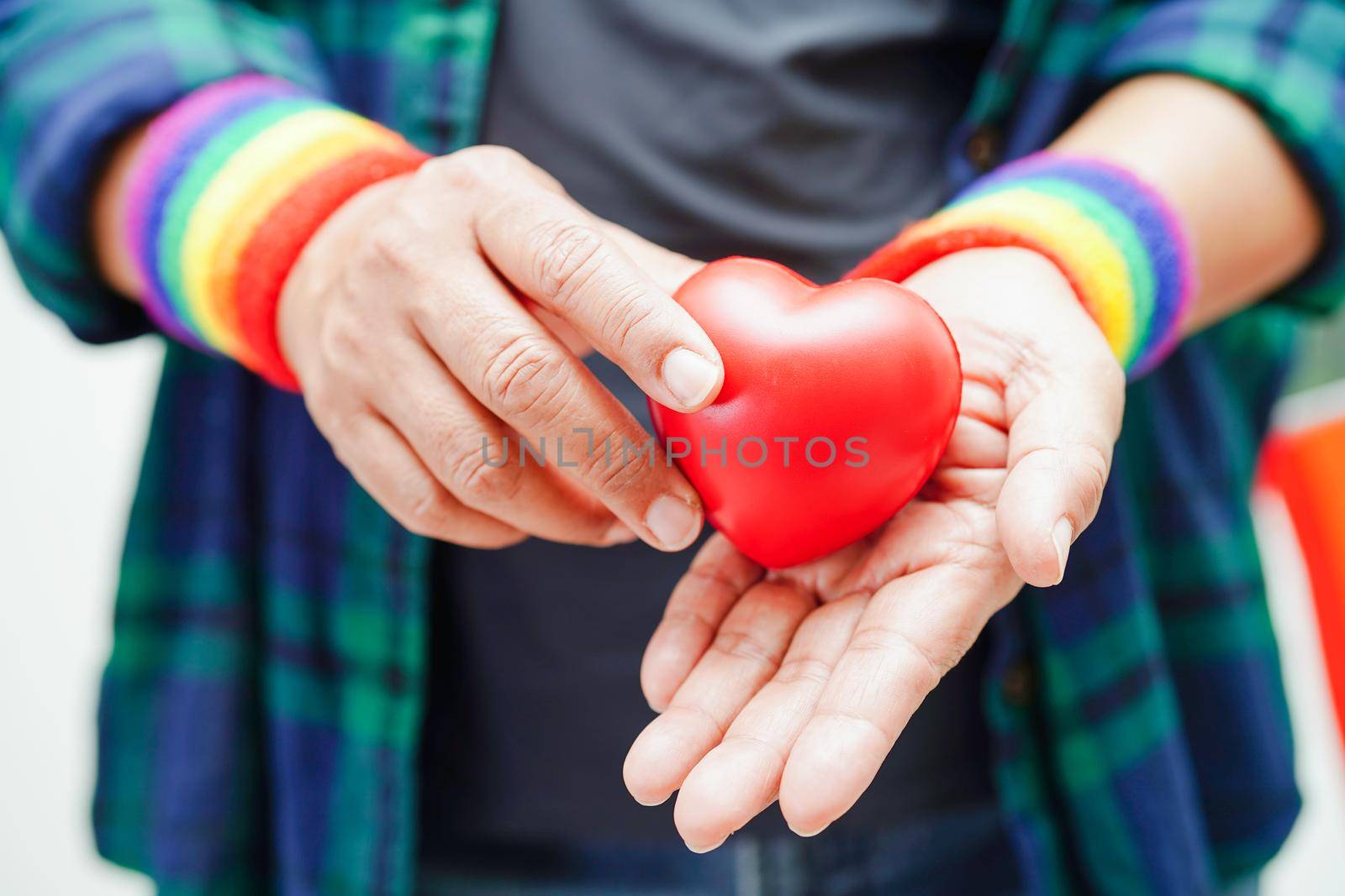 Asian woman holding red hert with rainbow flag, LGBT symbol rights and gender equality, LGBT Pride Month in June.
