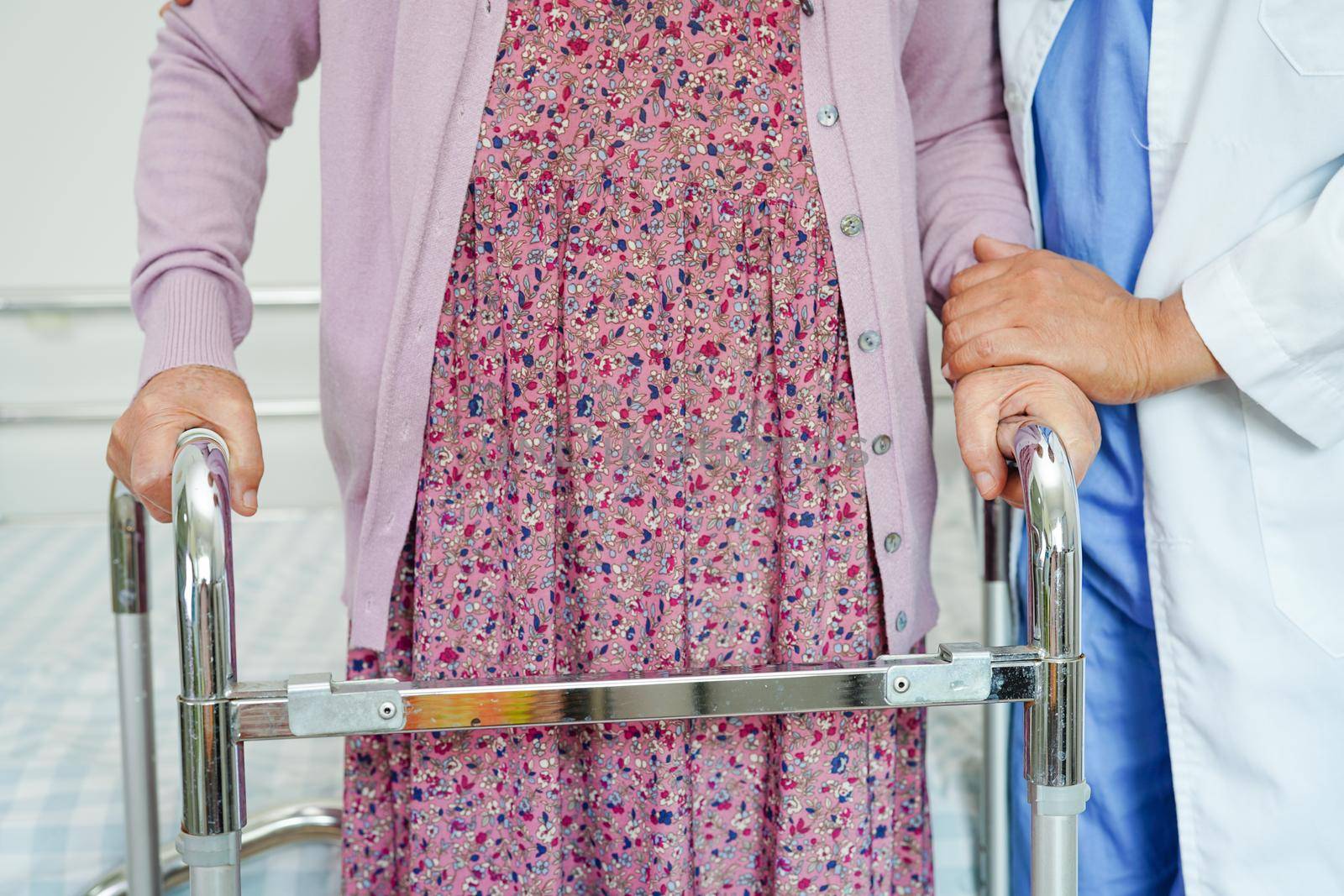 Doctor help Asian elderly woman disability patient walk with walker in nursing hospital, medical concept.