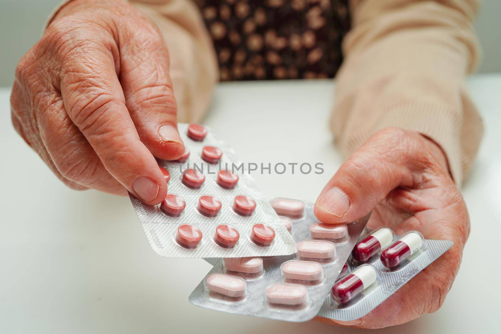 Asian elderly woman holding pill drug in hand, strong healthy medical concept. 