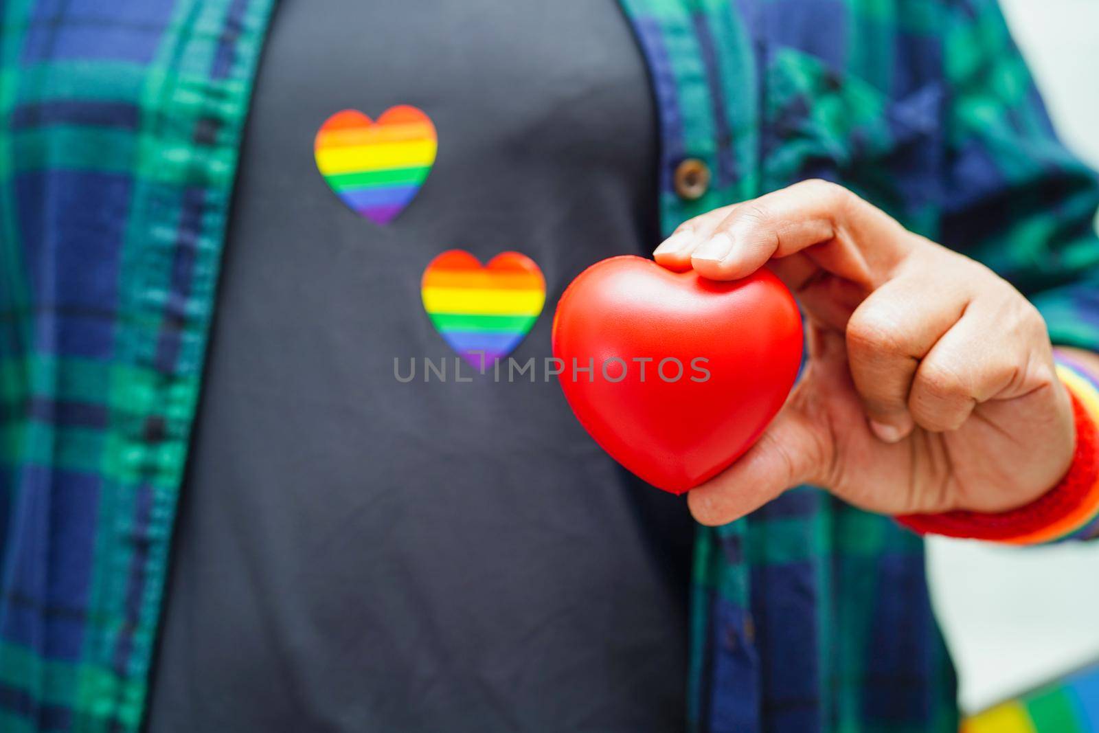 Asian woman holding red hert with rainbow flag, LGBT symbol rights and gender equality, LGBT Pride Month in June.