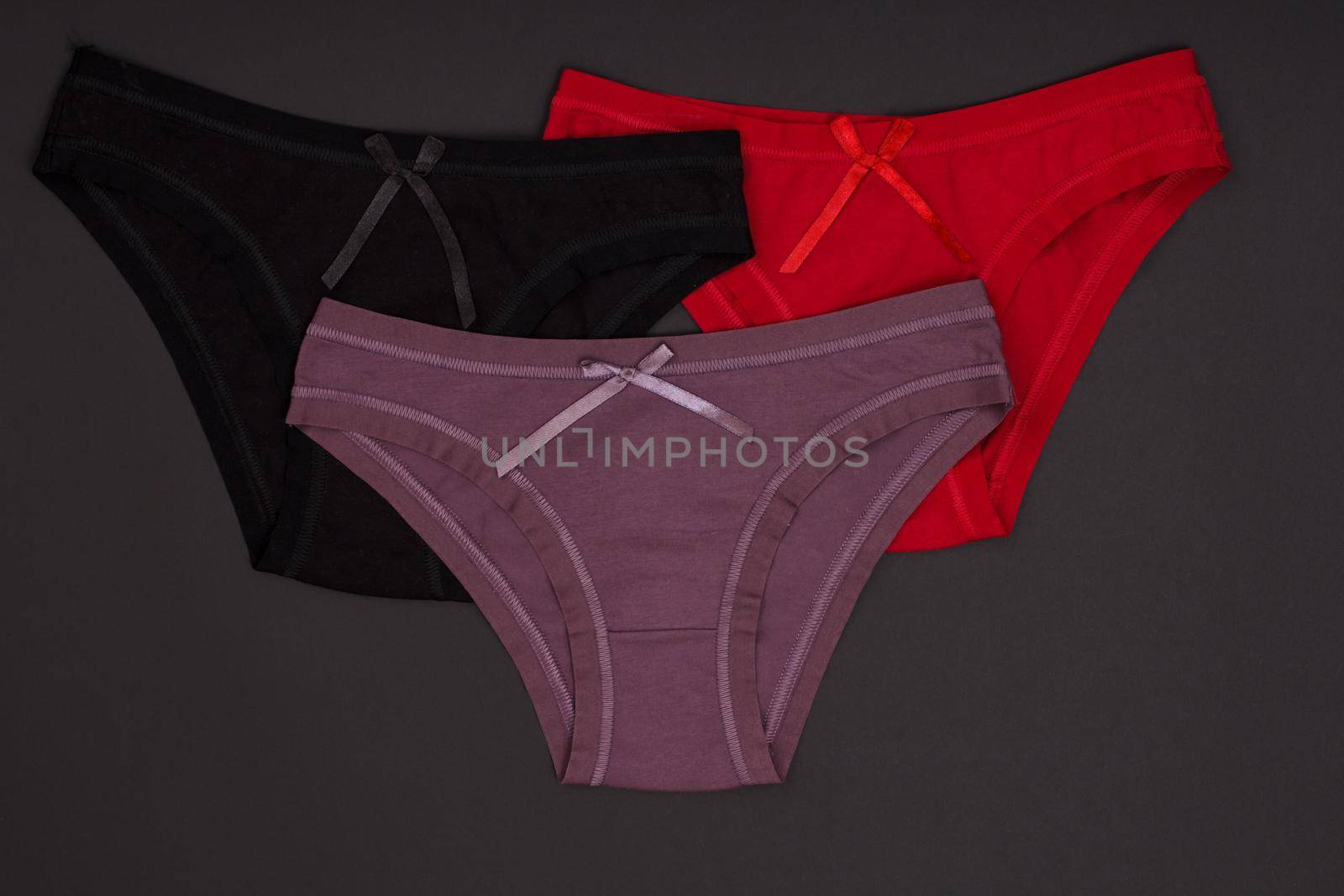 Beautiful black, brown and red cotton panties on the dark background. Woman underwear set. Top view.