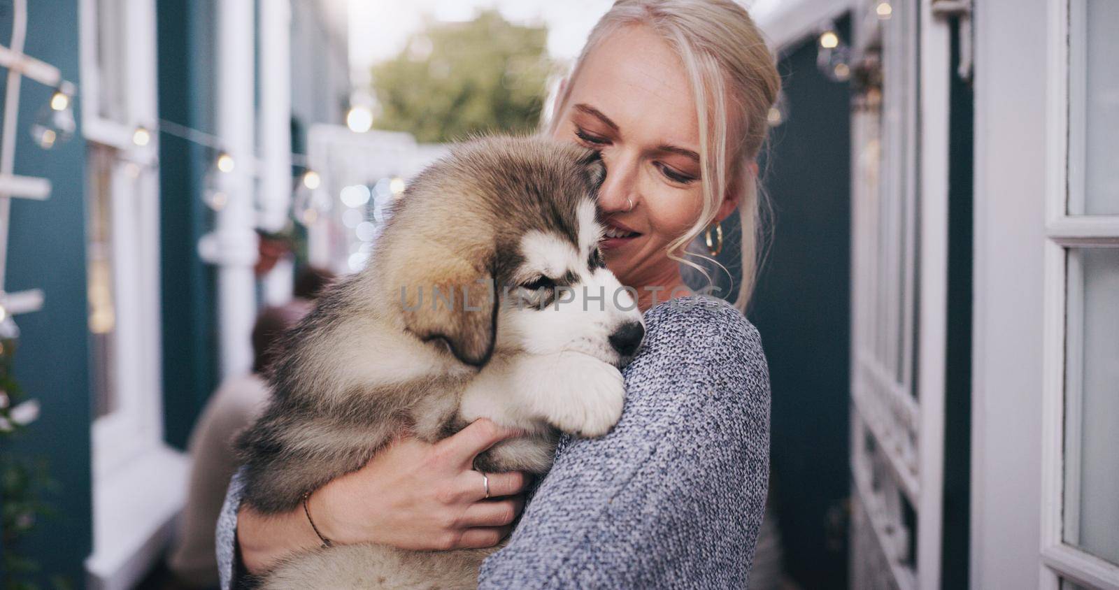 Give a dog love and hell give you loyalty. young woman cuddling her adorable husky puppy during a social gathering at home. by YuriArcurs