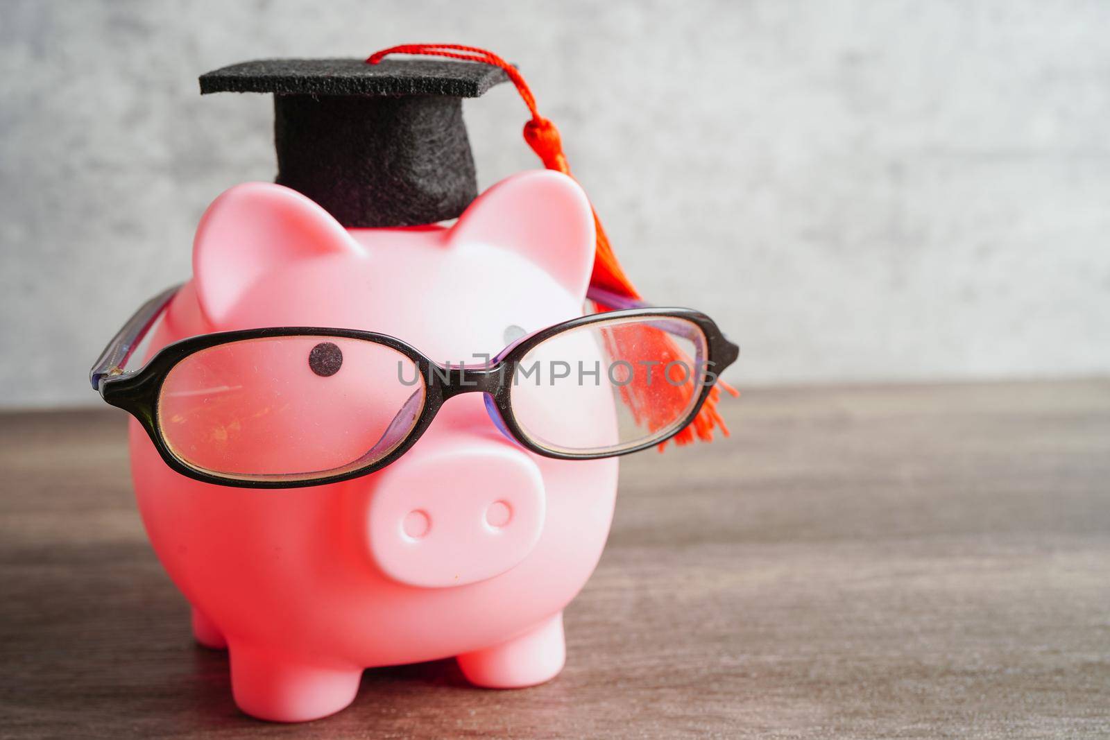 Pigging bank wearing eyeglass with coins and calculator saving bank education concept.