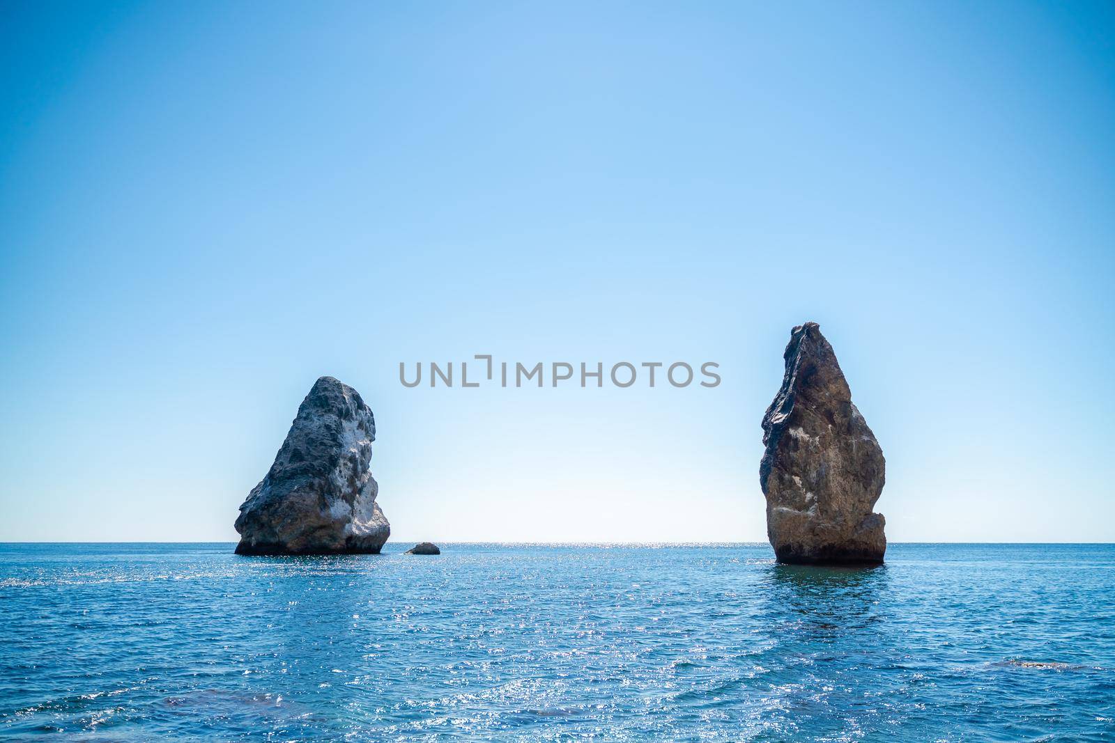 Two rocks stick out of the water in the middle of the turquoise sea. Scenic ocean views. High quality photo. Like in Iceland.