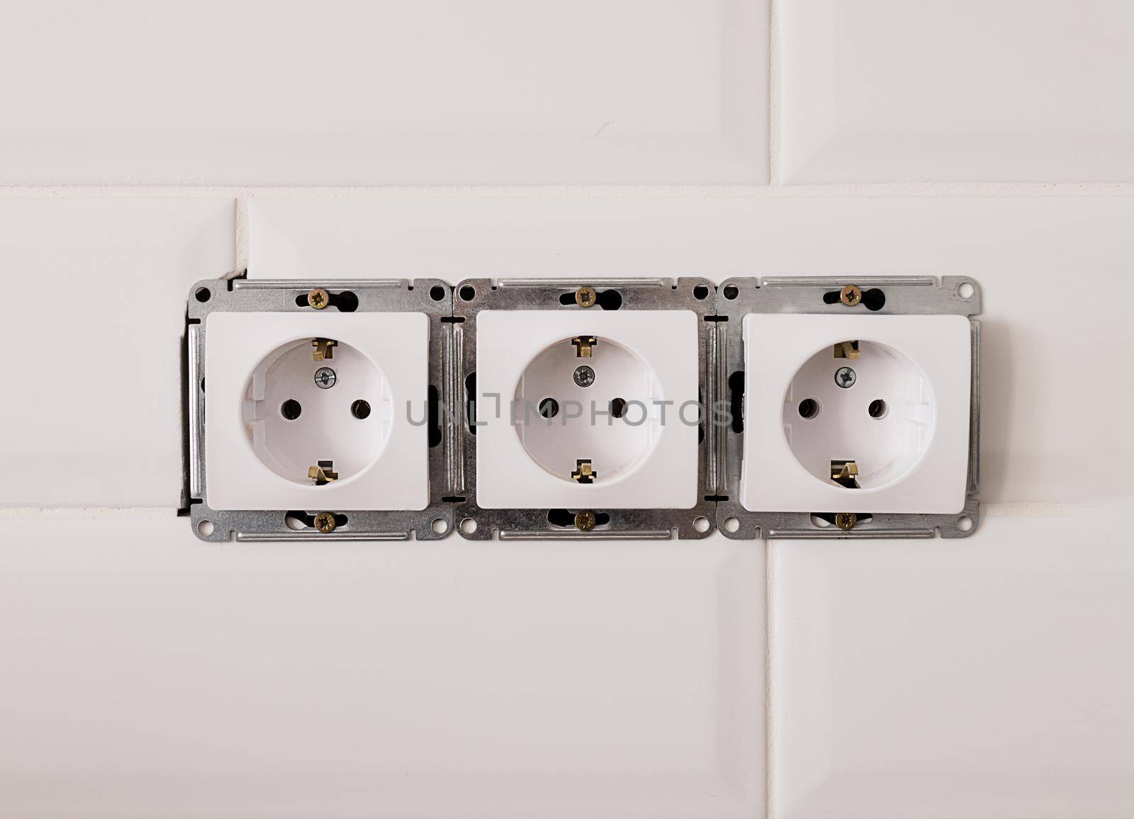 Close-up, three sockets on a white wall. Installation of electrical equipment, repair in the house. The concept of electrics, eco, reasonable power consumption.