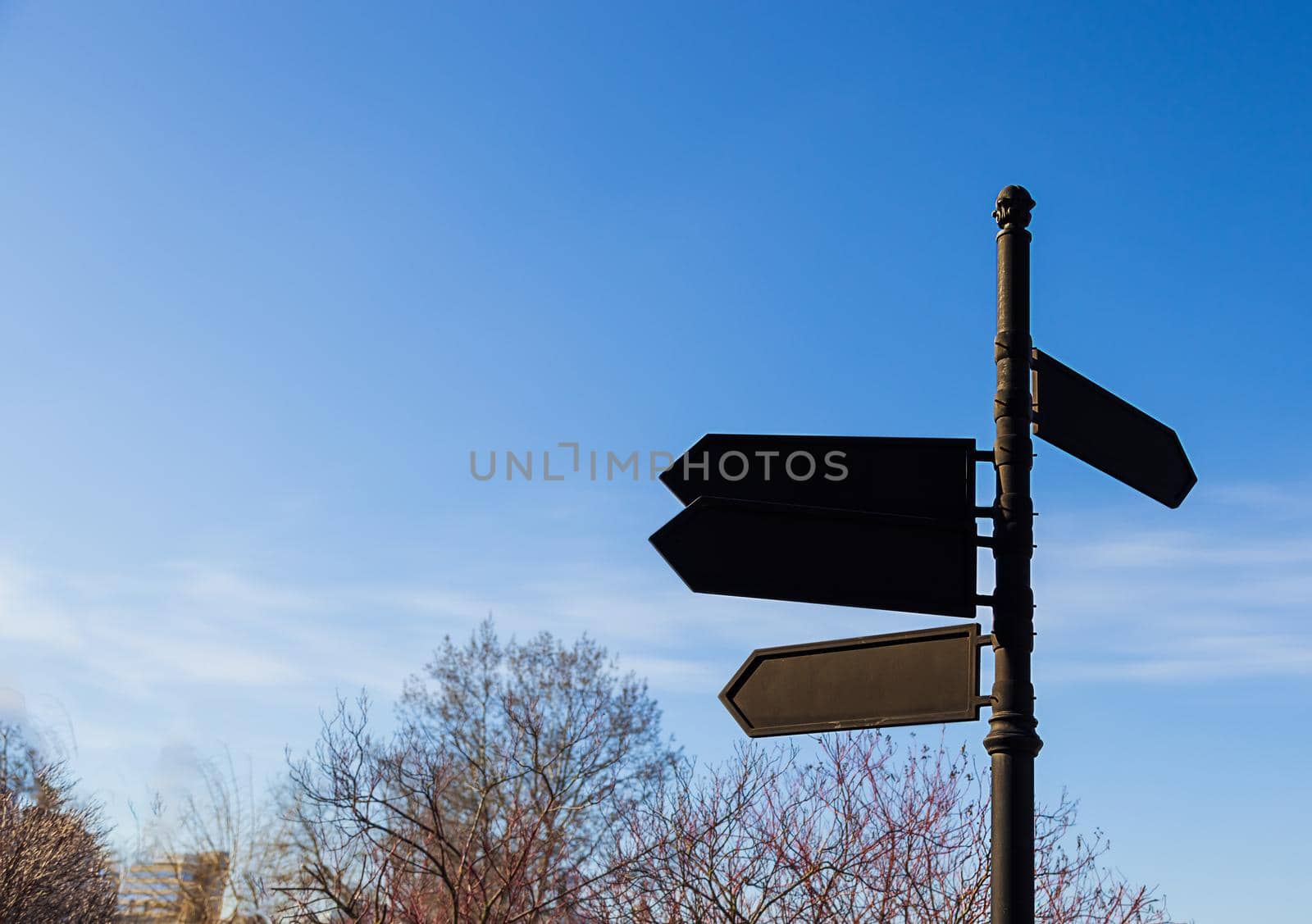 black, old pointer with arrows against the blue sky close-up. Urban landscape. Concept, point the way forward. Mockup, copy paste space for your design