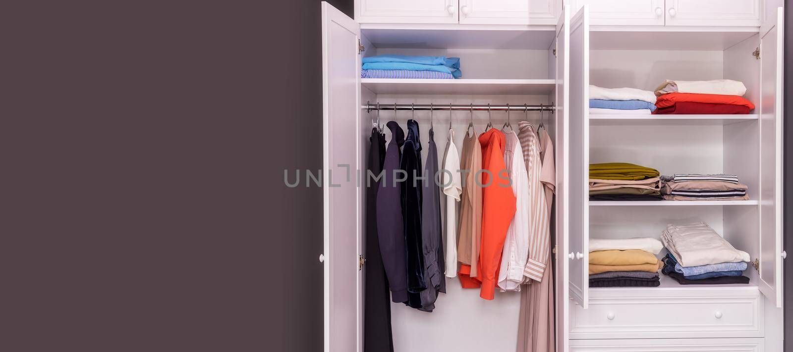 close-up of a white, open wardrobe with stylish women's items in one, light color scheme. Copy paste space for your design. The concept of organizing space, order, cleaning, reasonable consumption.
