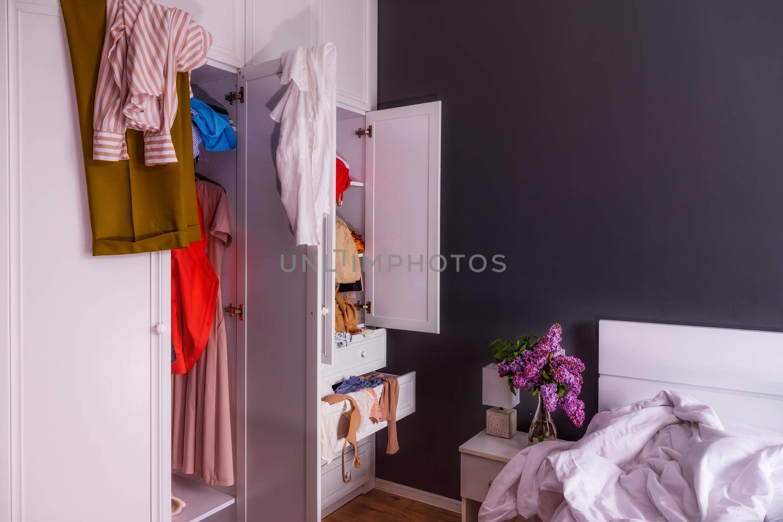 Close-up of a large white closet in which clothes are in disarray. Colored things are scattered around the room. The concept of cleaning, washing, organizing things. Copy paste