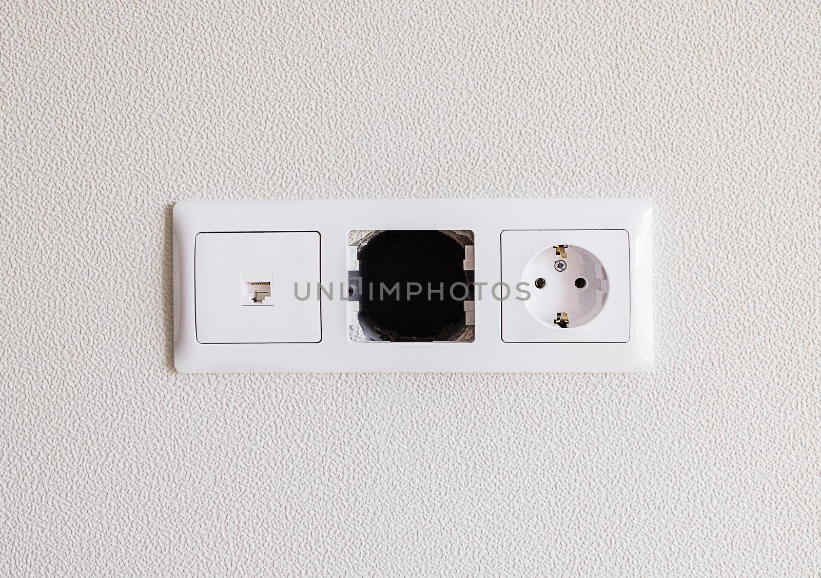 close-up electrical and internet socket, with an empty space in the center. New, white equipment against a white wall. The concept of repair, installation of new equipment