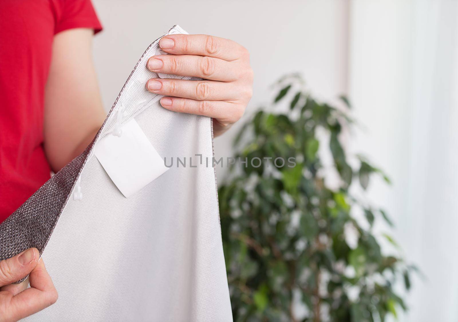 close-up, female hands demonstrate a piece of white fabric, mockup label. by Ramanouskaya
