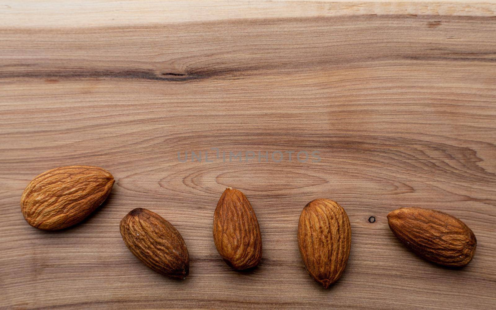 Almonds taken in close-up on a wooden background. Healthy eating and vegetarianism. The concept of healthy lifestyle. by Matiunina