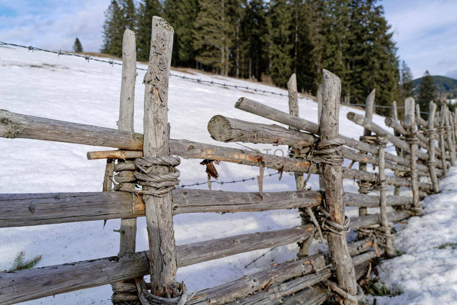 An old wooden fence that is held together with willow rods.